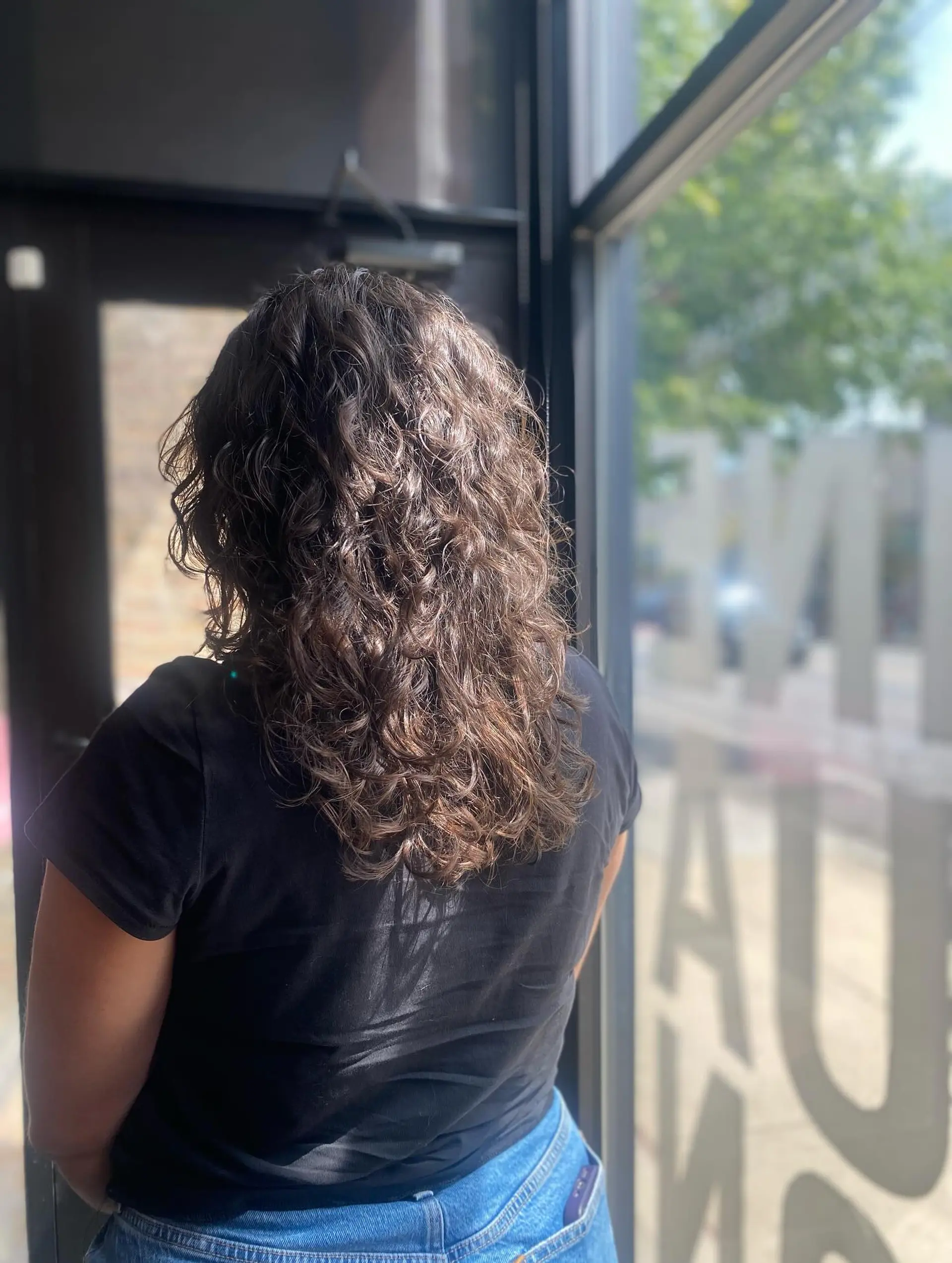 A medium-length curly hairstyle featuring a bronde balayage. 3