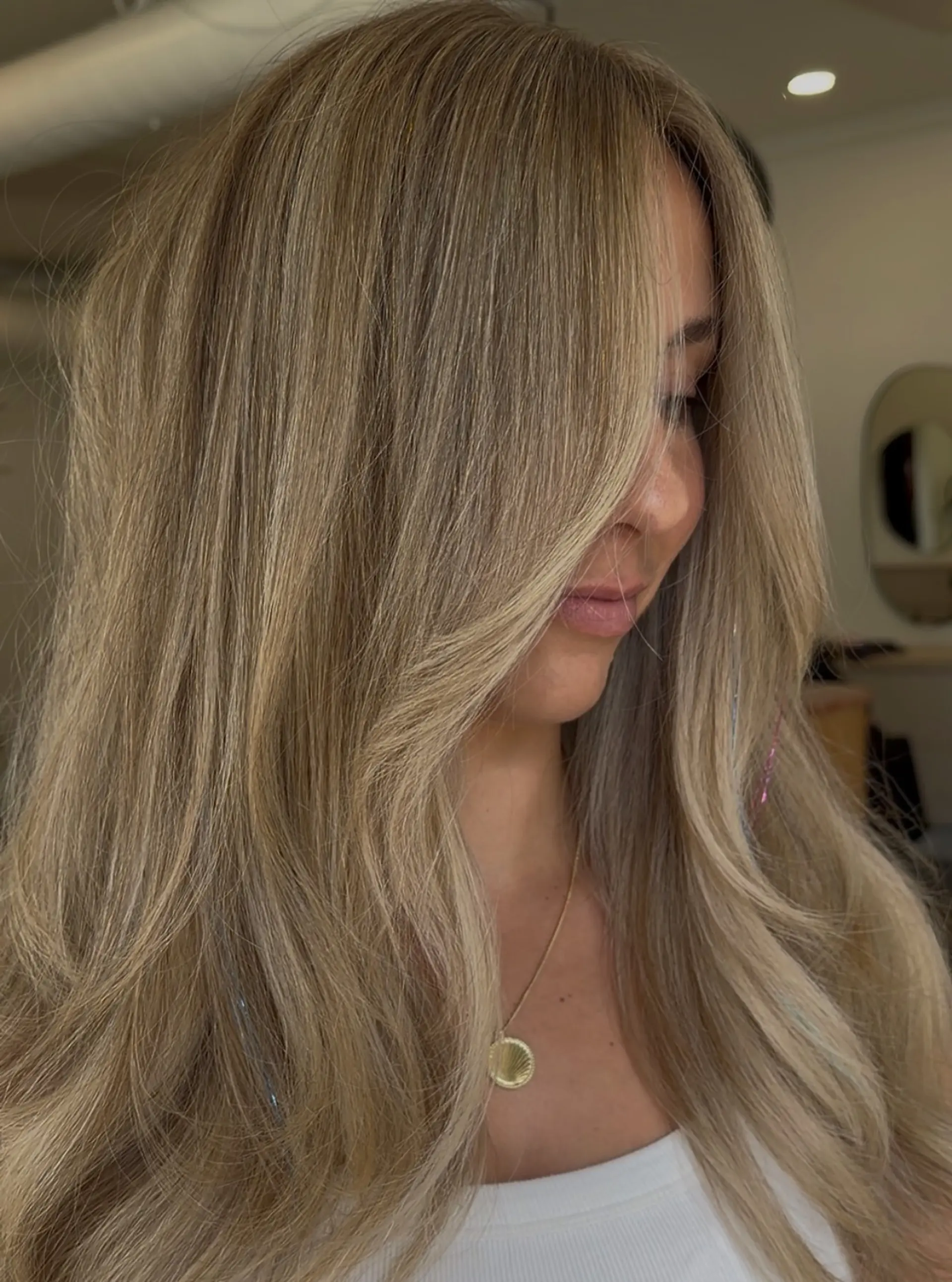 Long dimensional blonde hair styled in a voluminous blowout with face-framing layers and hair tinsel accents. 1