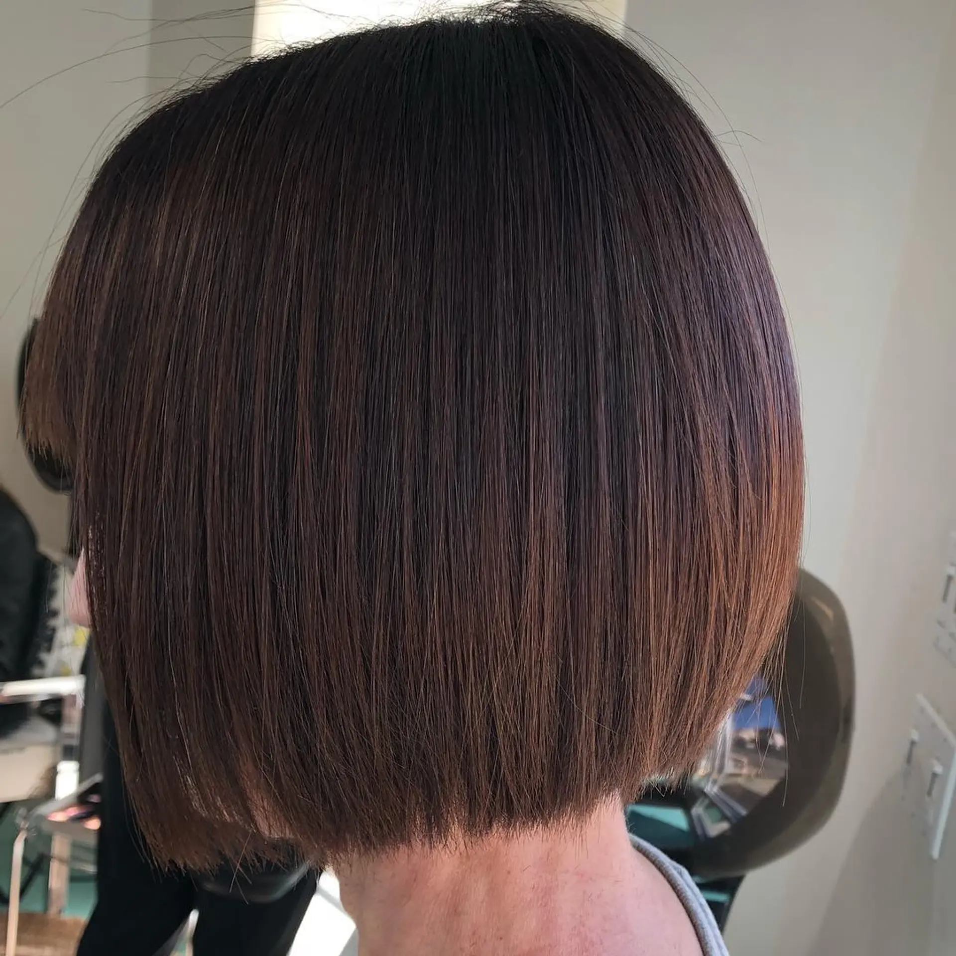 A sleek, chin-length precision bob with softly texturized blunt ends in a rich, warm dark brown. 1