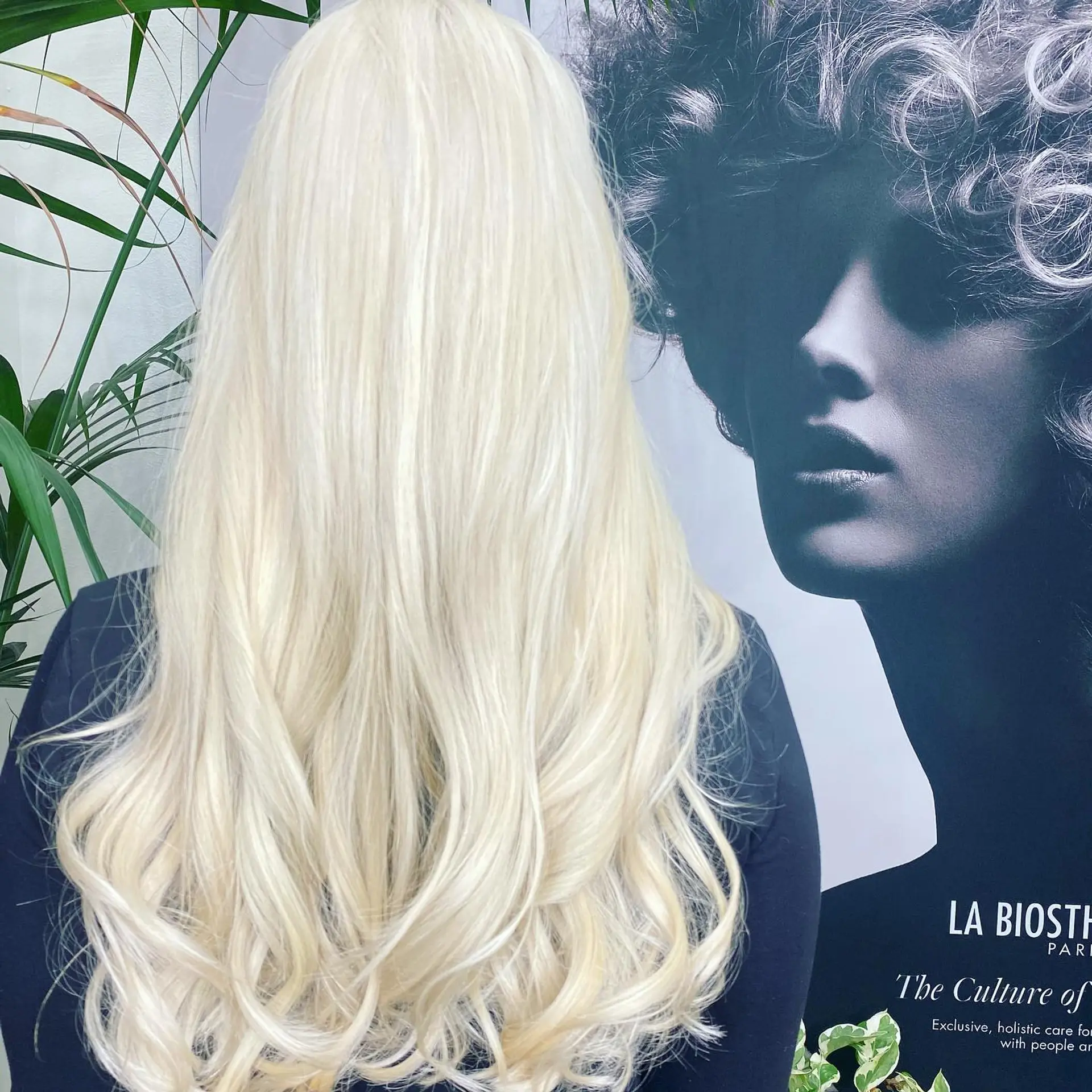 Long, seamless platinum blonde hair styled smooth with loose, bouncy waves toward the ends. 1