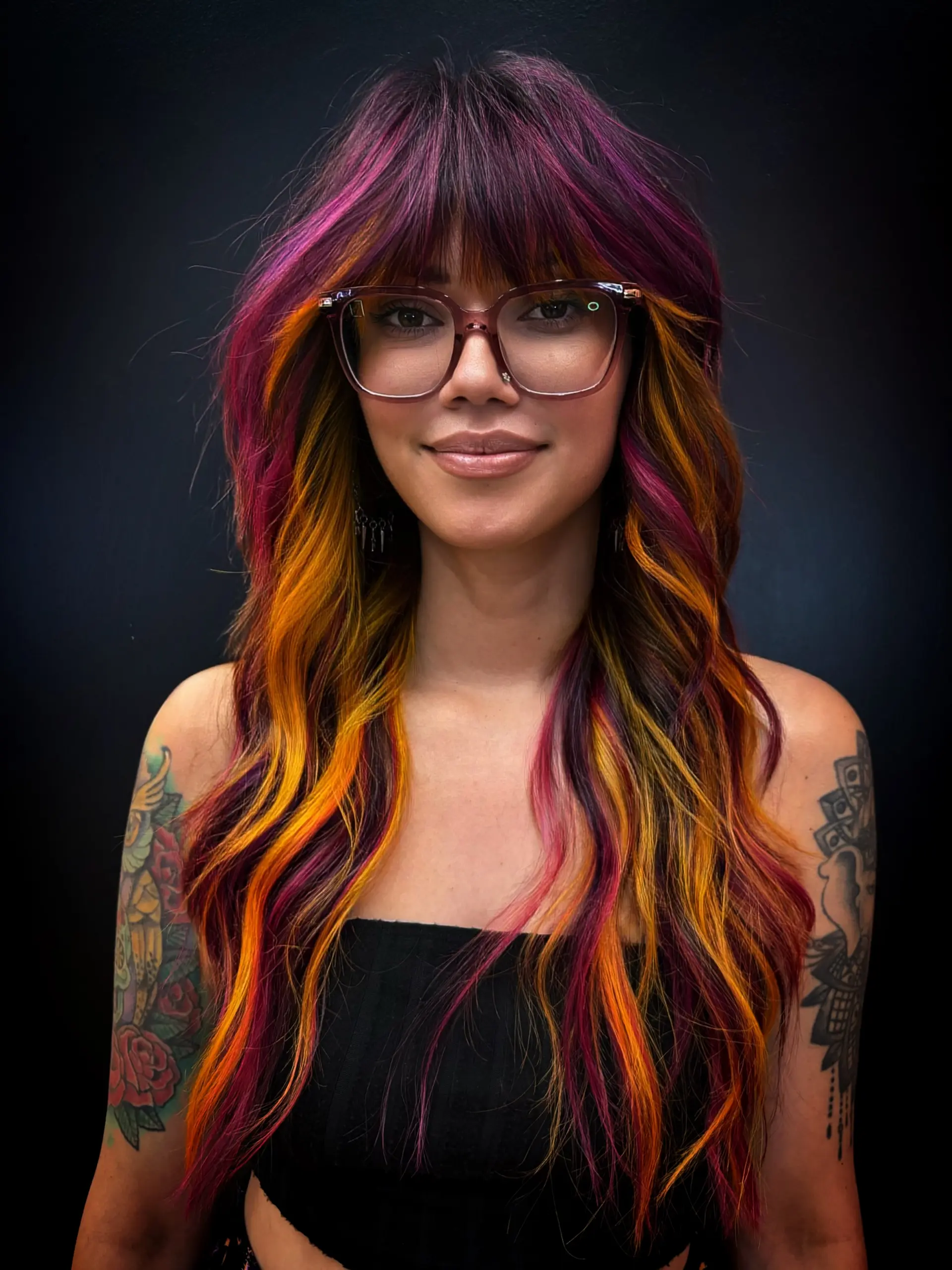 A textured long shag with full fringe bangs featuring bold color placement in rich magenta-purple and bright sunset yellow-orange. 1