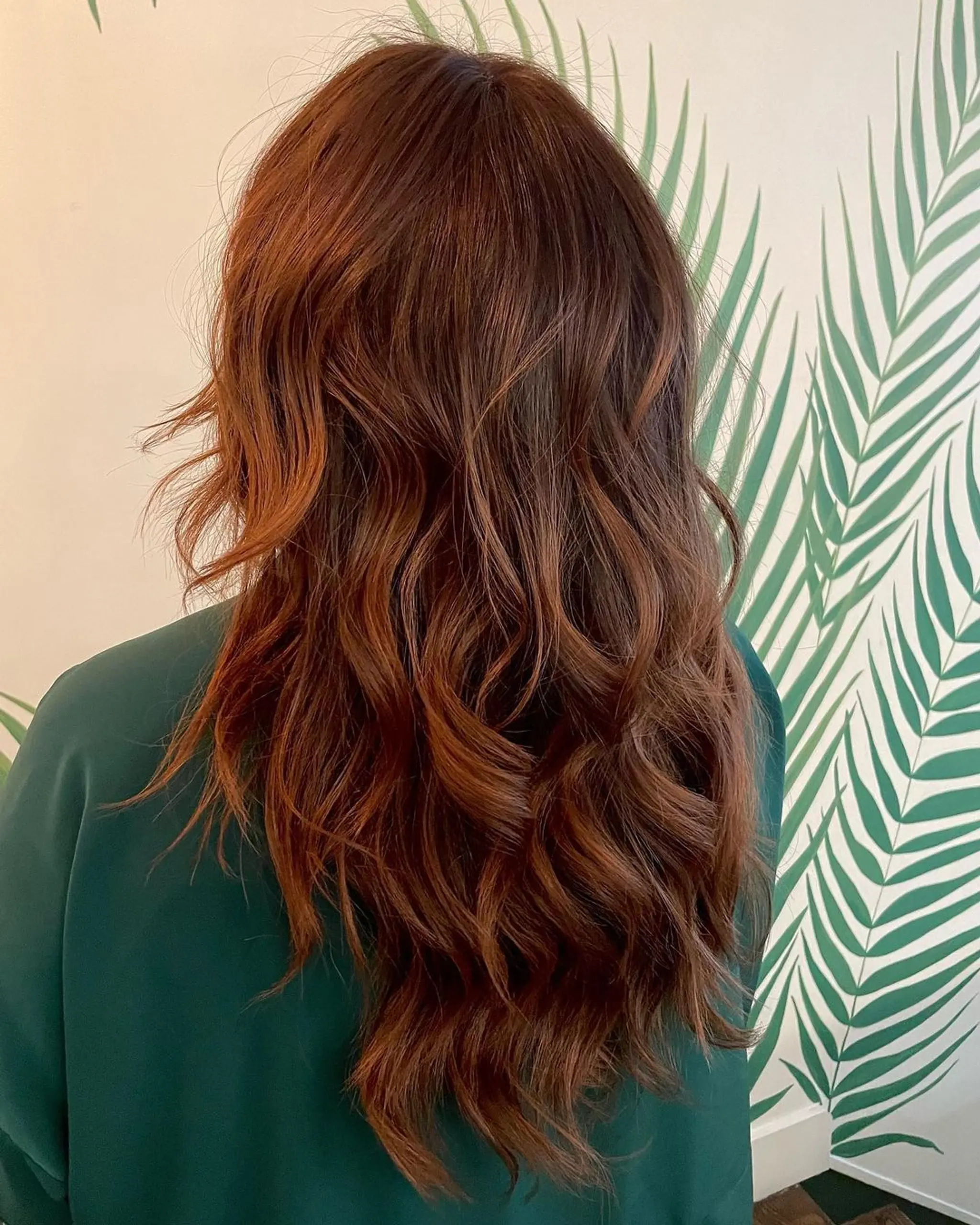 Long wavy hair with an ombre effect transitioning from black to auburn, featuring natural waves and subtle layers.