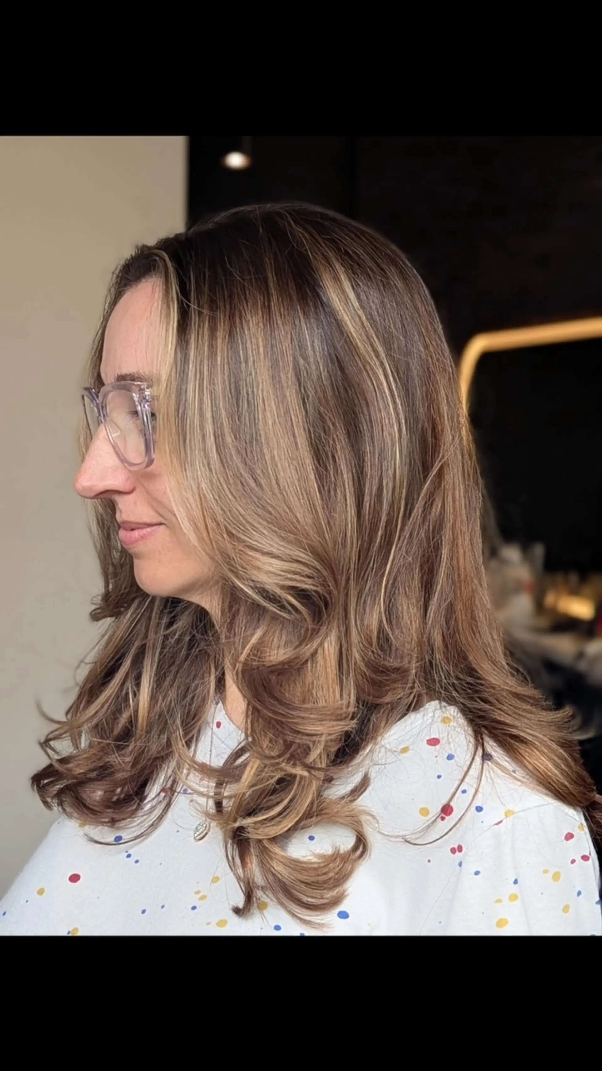 Medium-to-long layered bronde hair featuring soft, face-framing layers and styled with curled, bouncy ends. 1