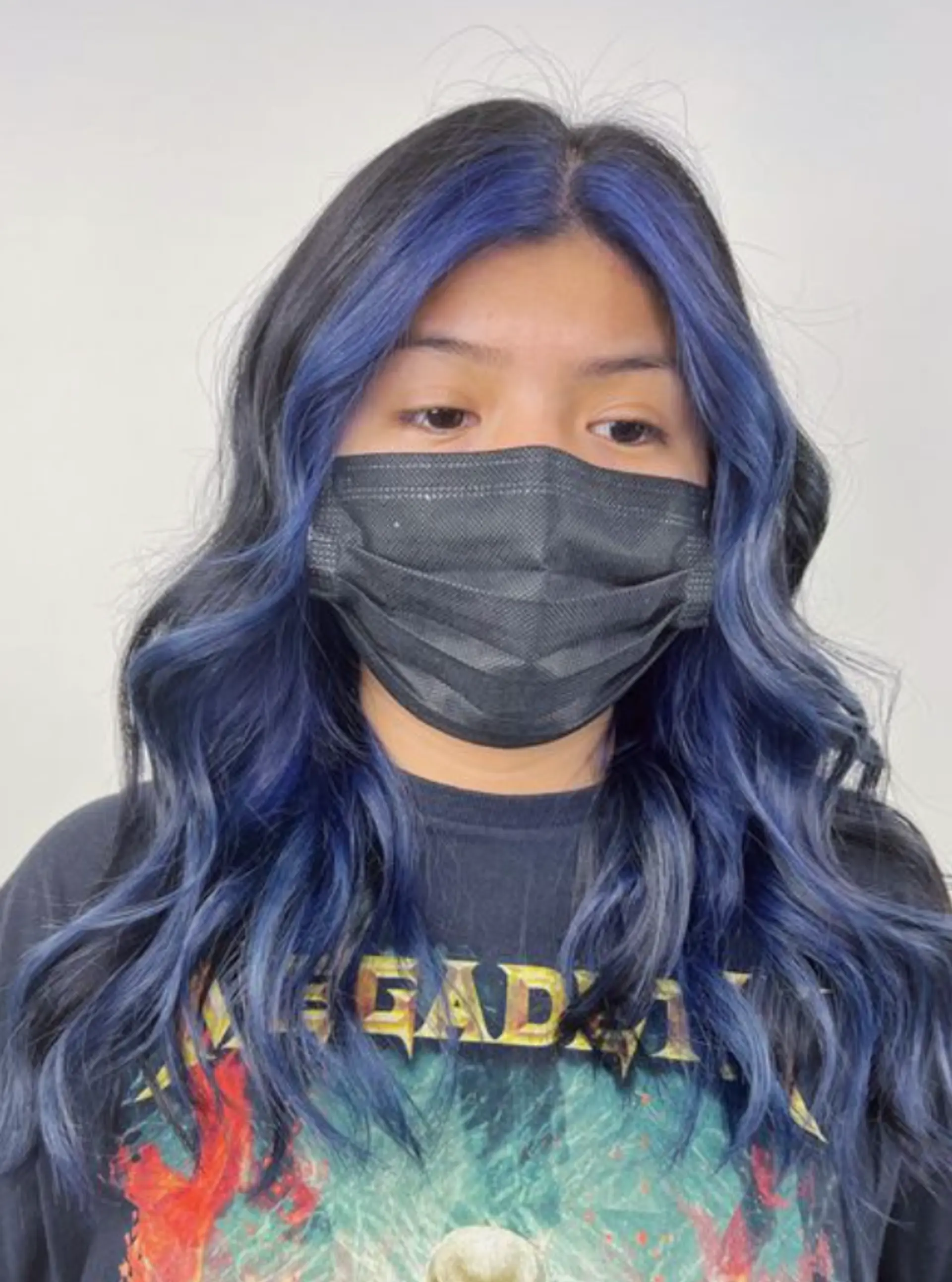 Long, wavy black hair with electric blue balayage, styled in loose beach waves with face-framing strands. 1