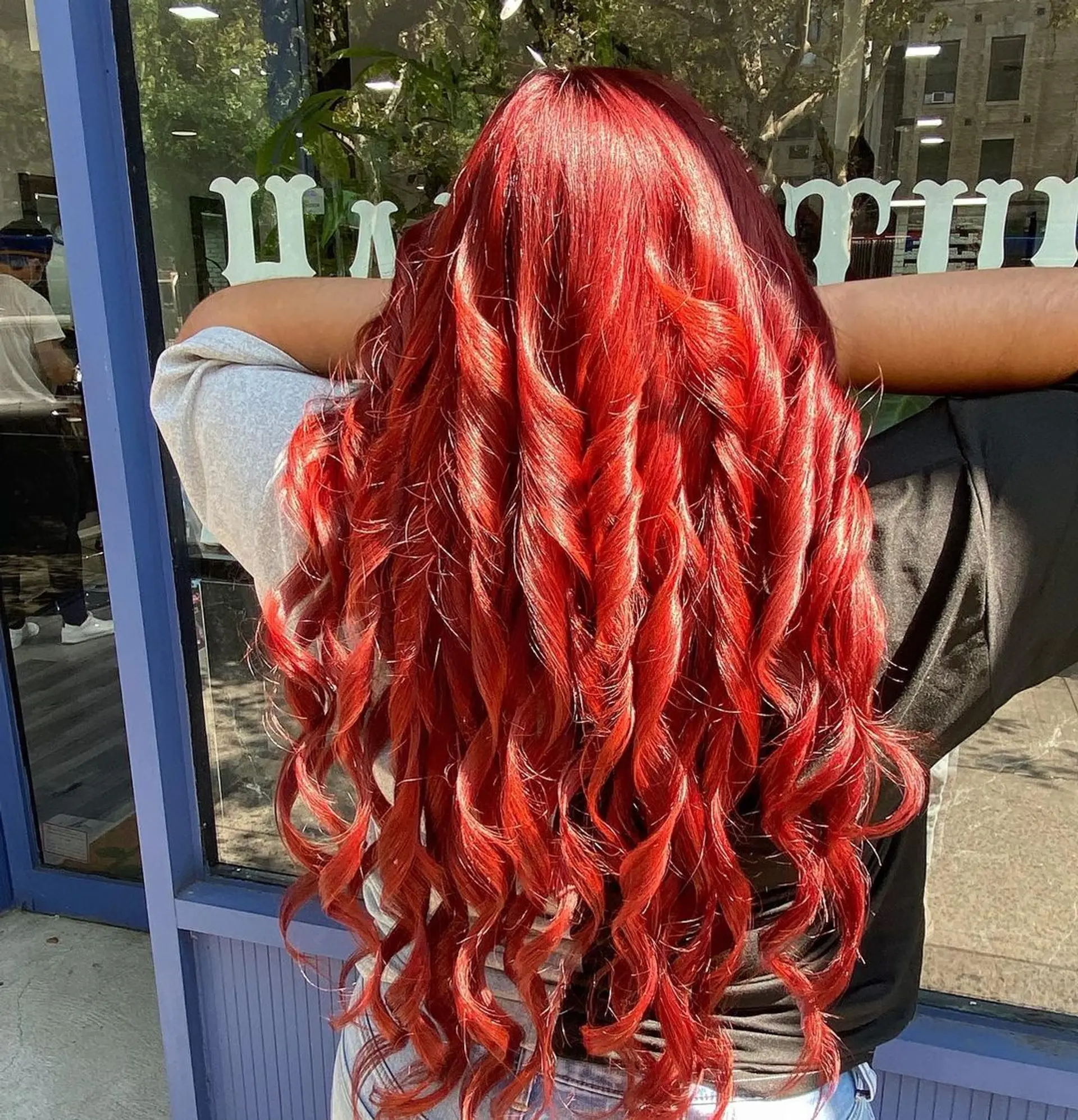 The hairstyle features very long, curly hair in a vibrant red color, styled in loose, spiral waves creating a bouncy, voluminous look. By emily_hair_nyc 1