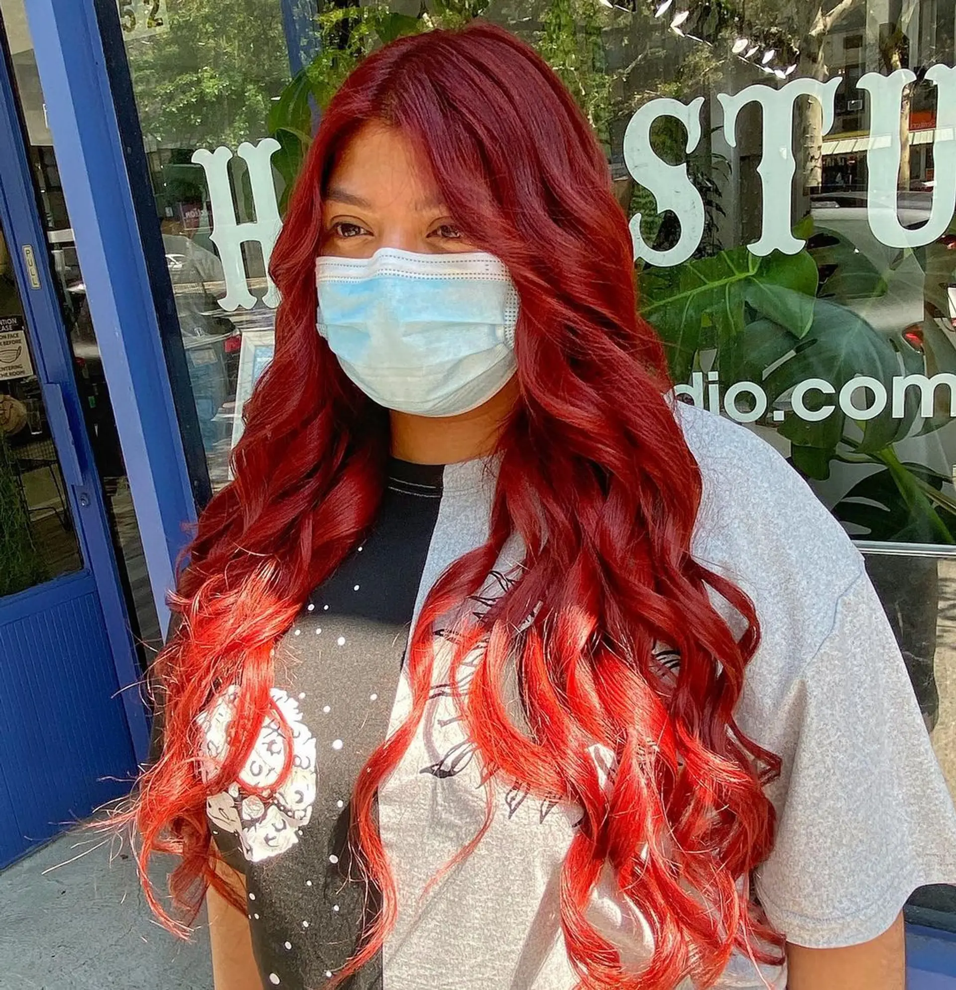The hairstyle features very long, curly hair in a vibrant red color, styled in loose, spiral waves creating a bouncy, voluminous look. By emily_hair_nyc 2