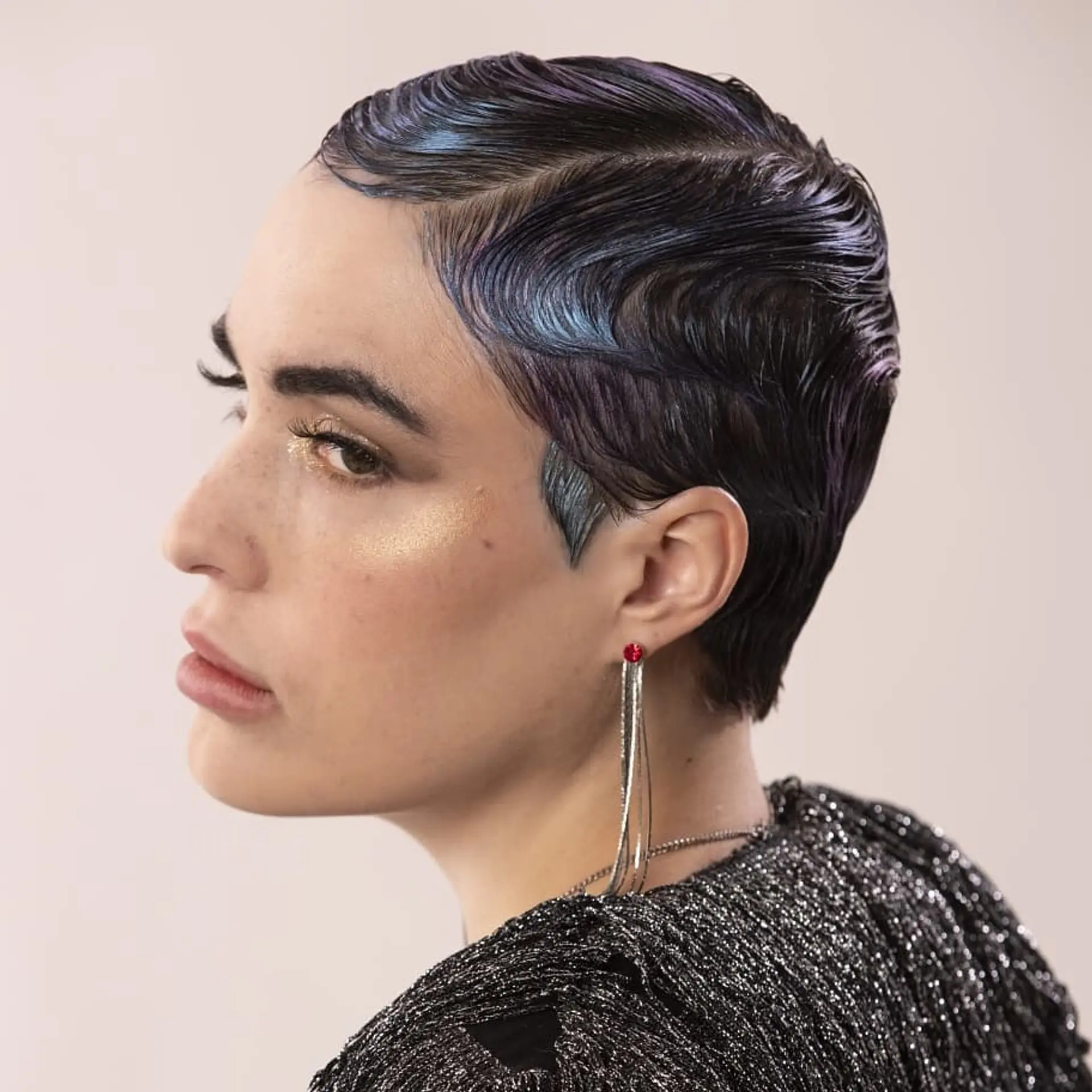 A short, wavy pixie cut styled in finger waves with iridescent coloring. 1