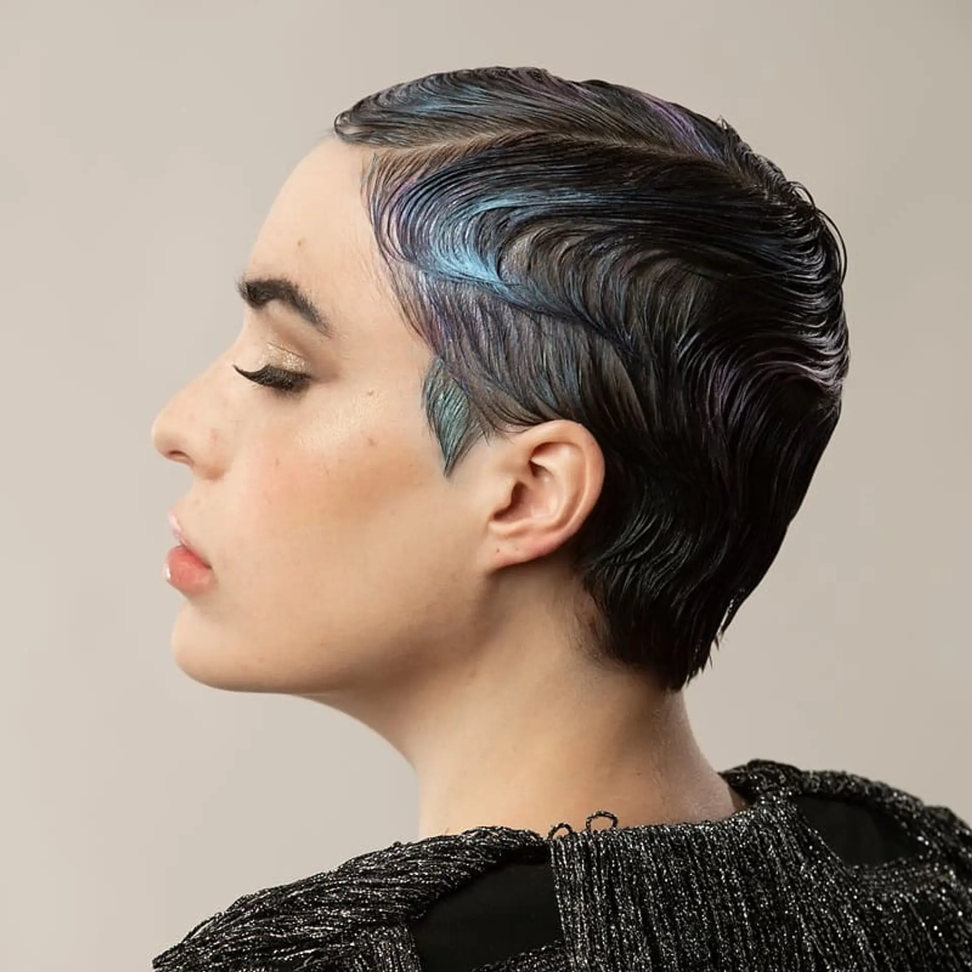 A short, wavy pixie cut styled in finger waves with iridescent coloring. 2