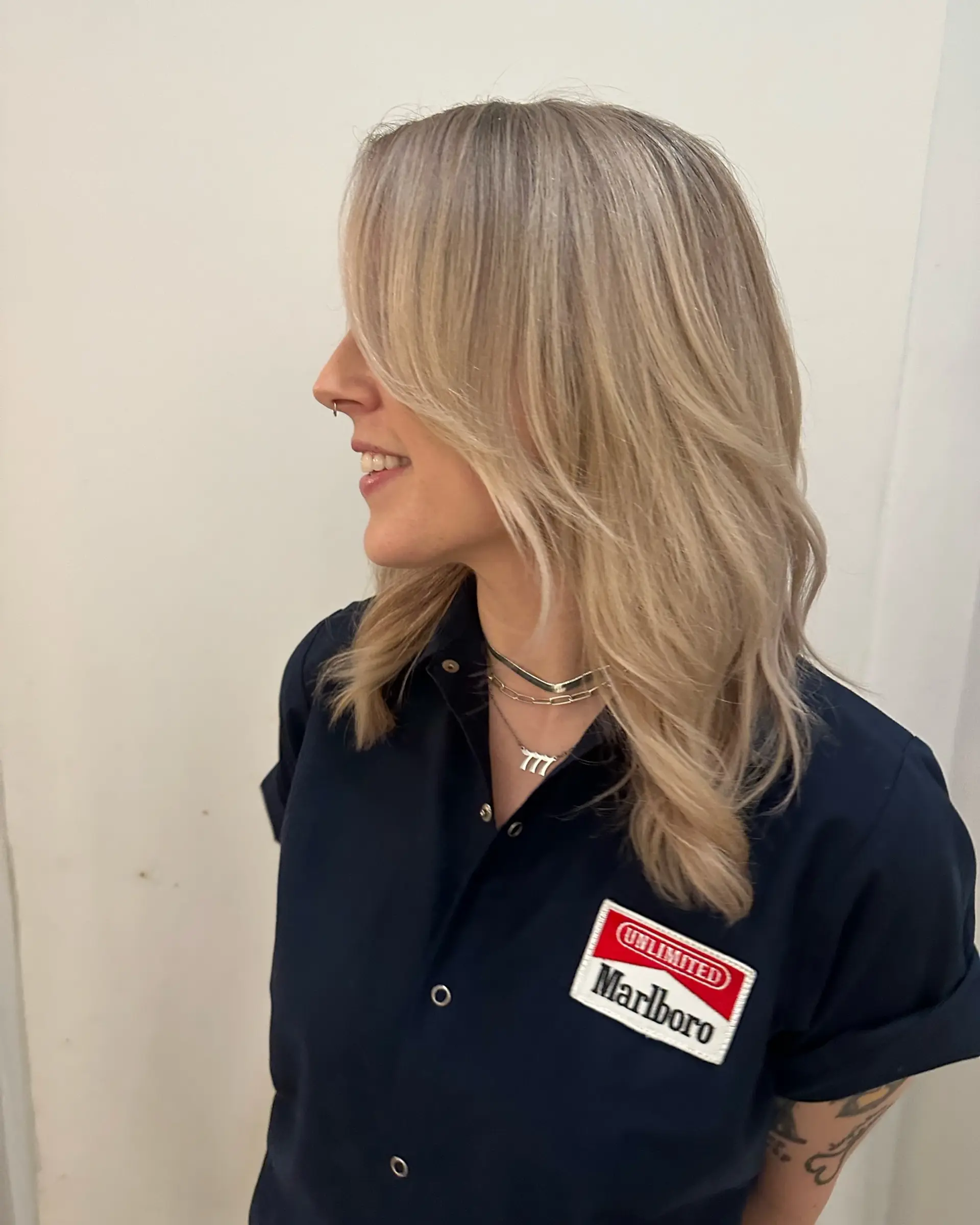 Medium-length ash blonde hair cut with blended layers, long face-framing fringe, and soft, textured waves. 1