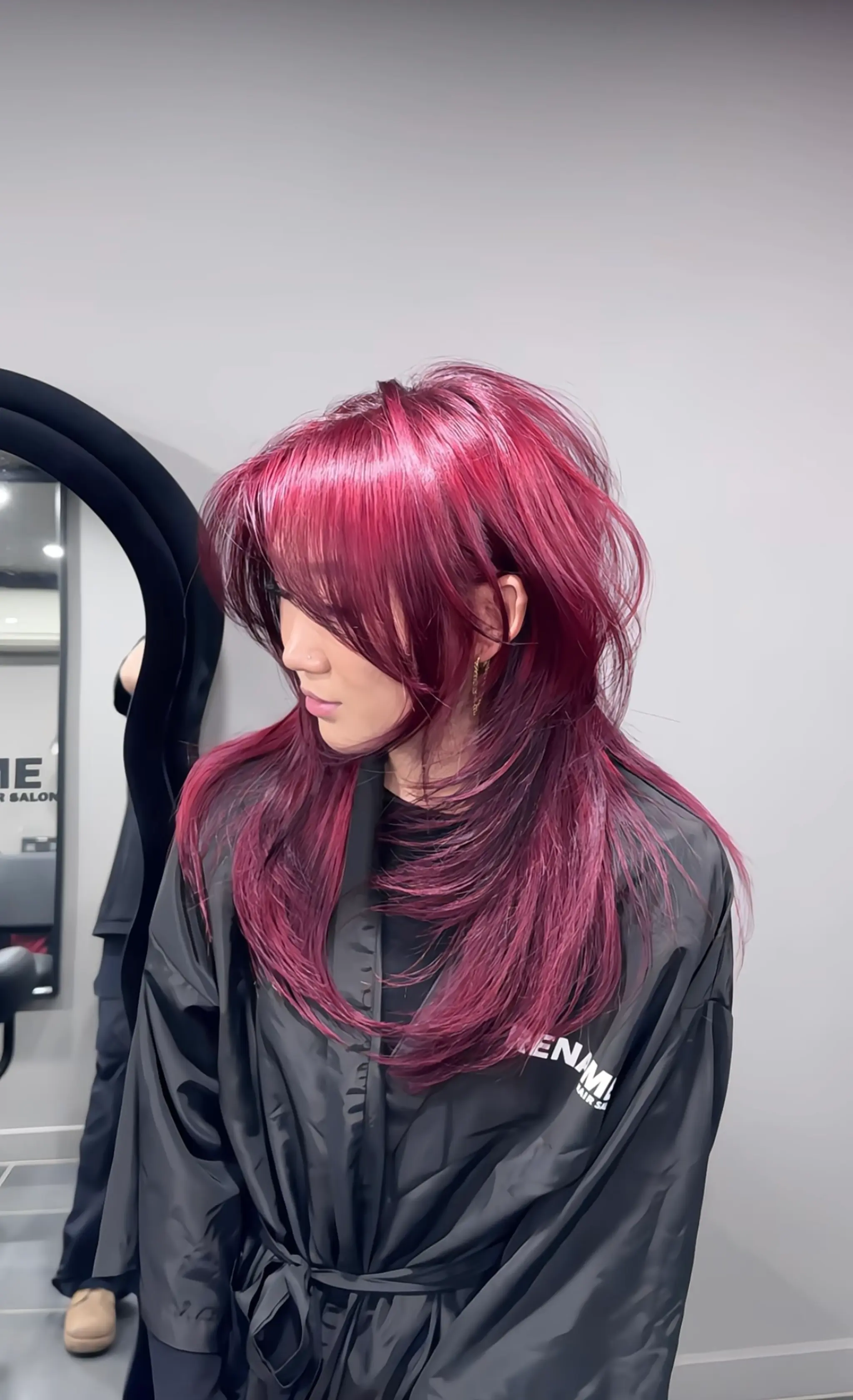The hairstyle is a long, layered look with straight texture and a vibrant burgundy hue. It features voluminous layers and side-swept bangs, creating a dynamic and textured appearance. 1