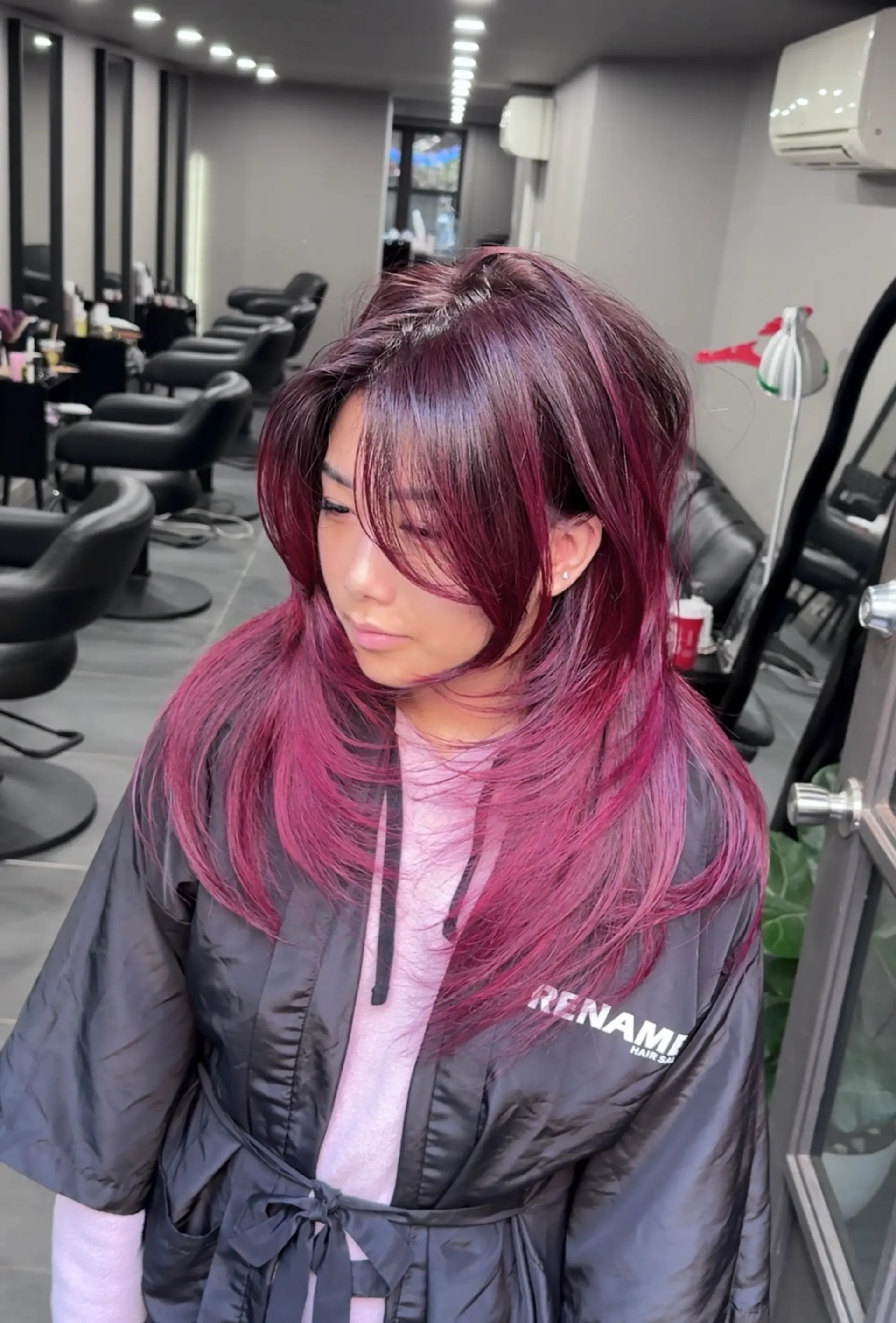The hairstyle is a long, layered look with straight texture and a vibrant burgundy hue. It features voluminous layers and side-swept bangs, creating a dynamic and textured appearance. 2