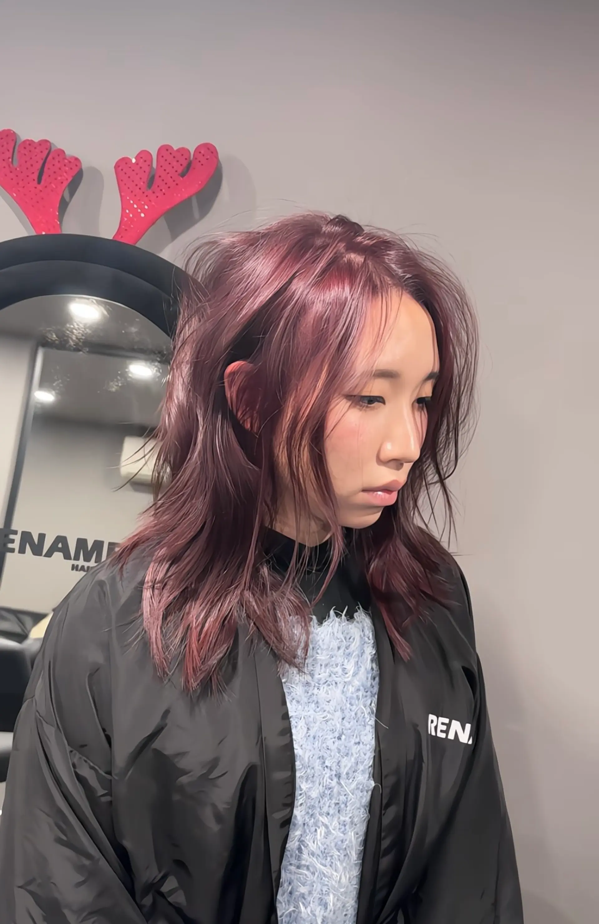 The hairstyle is a long, layered look with straight texture and a vibrant burgundy hue. It features voluminous layers and side-swept bangs, creating a dynamic and textured appearance. 3