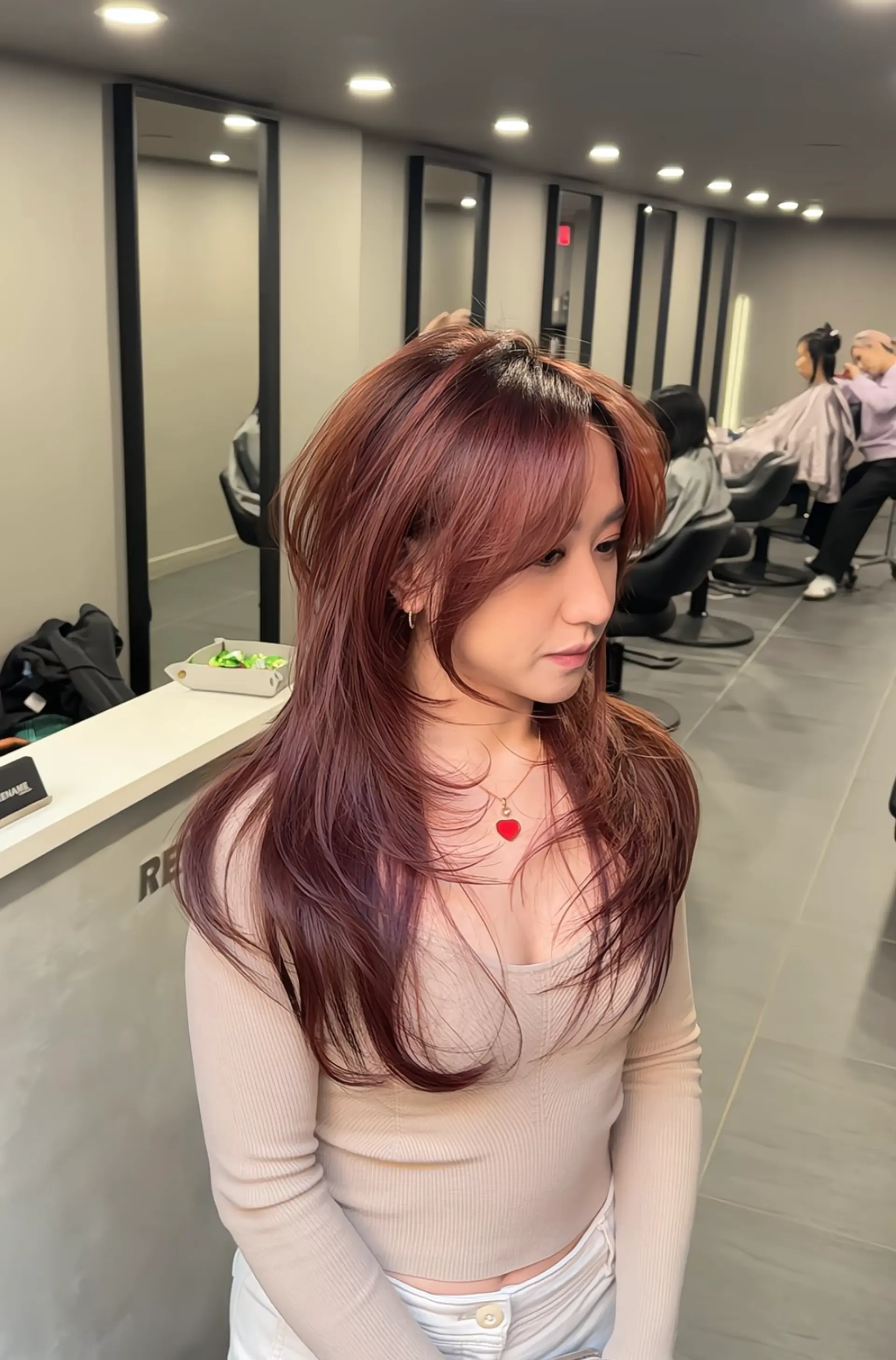 The hairstyle is a long, layered look with straight texture and a vibrant burgundy hue. It features voluminous layers and side-swept bangs, creating a dynamic and textured appearance. 6