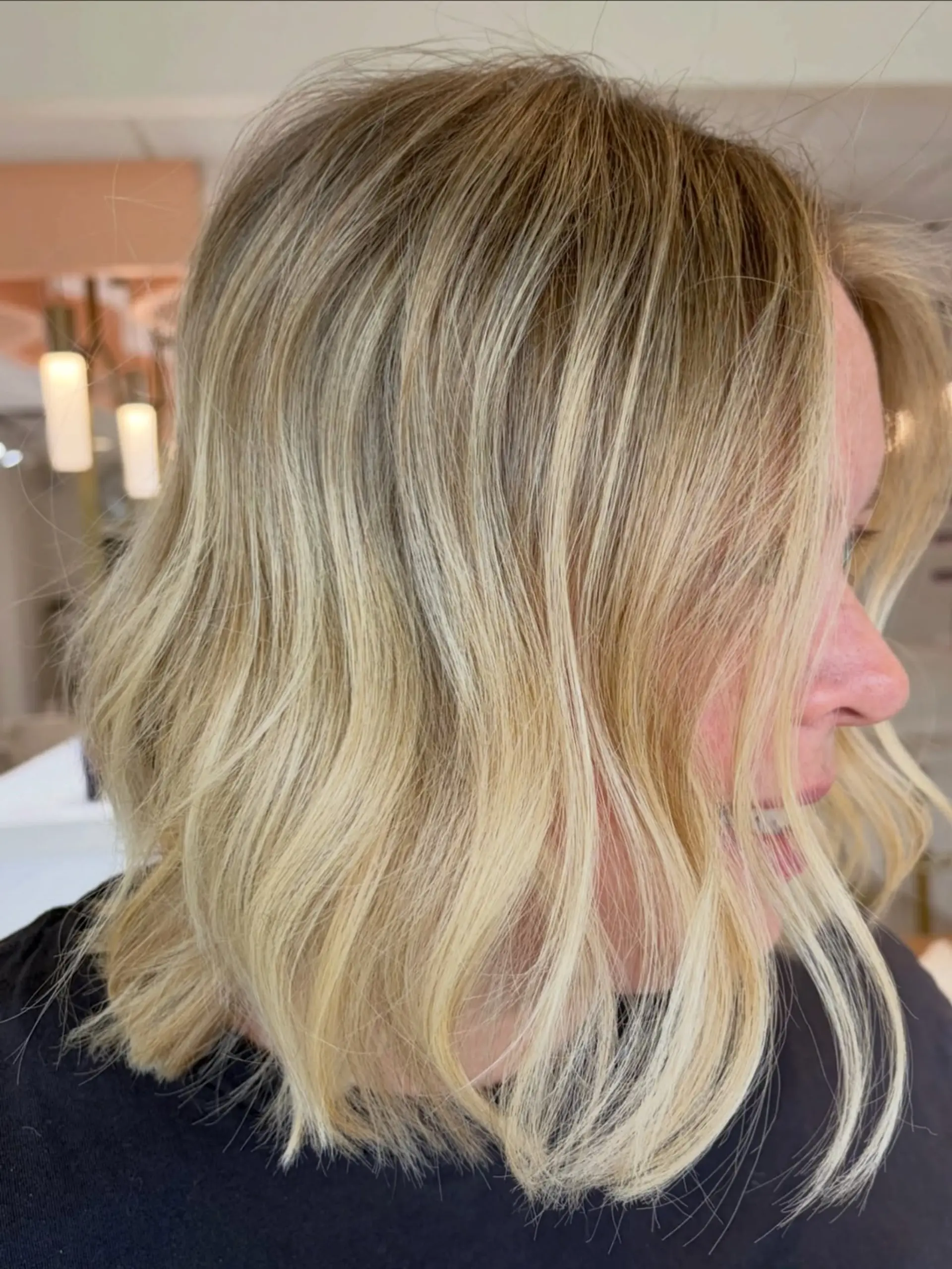 A textured shoulder-length bob styled in soft, loose waves featuring dimensional bright blonde highlights. 1