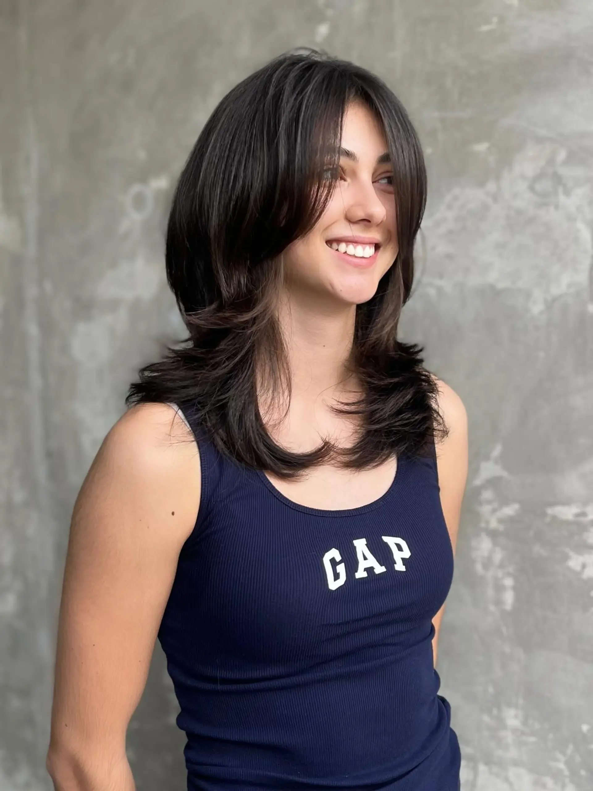 A medium-length textured shag haircut featuring sweeping curtain bangs, heavy face-framing layers, and flipped feathered ends. 1