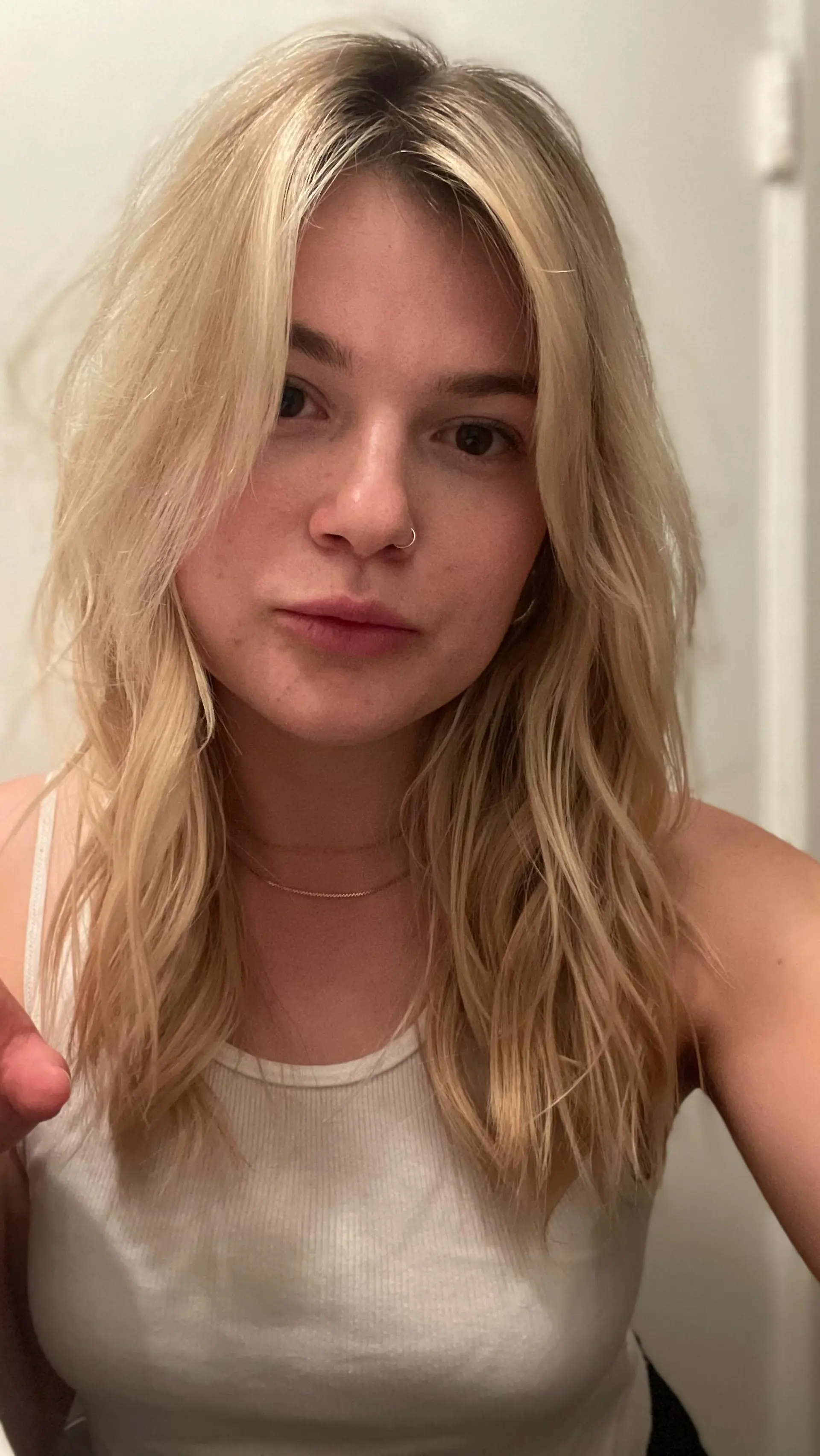 Medium-length blonde hairstyle featuring curtain bangs, layered face-framing pieces, and soft textured waves enhanced by tape-in extensions. 1