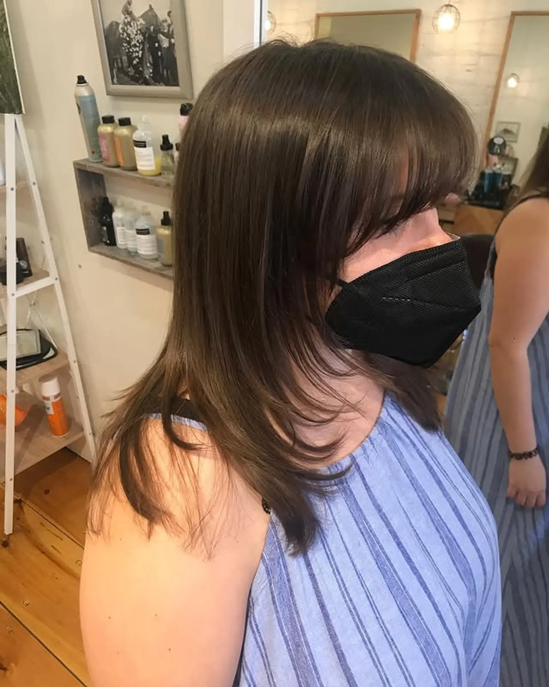 This hairstyle features curtain bangs that frame the face beautifully, paired with soft layers that add movement and dimension throughout the medium-length hair. 1