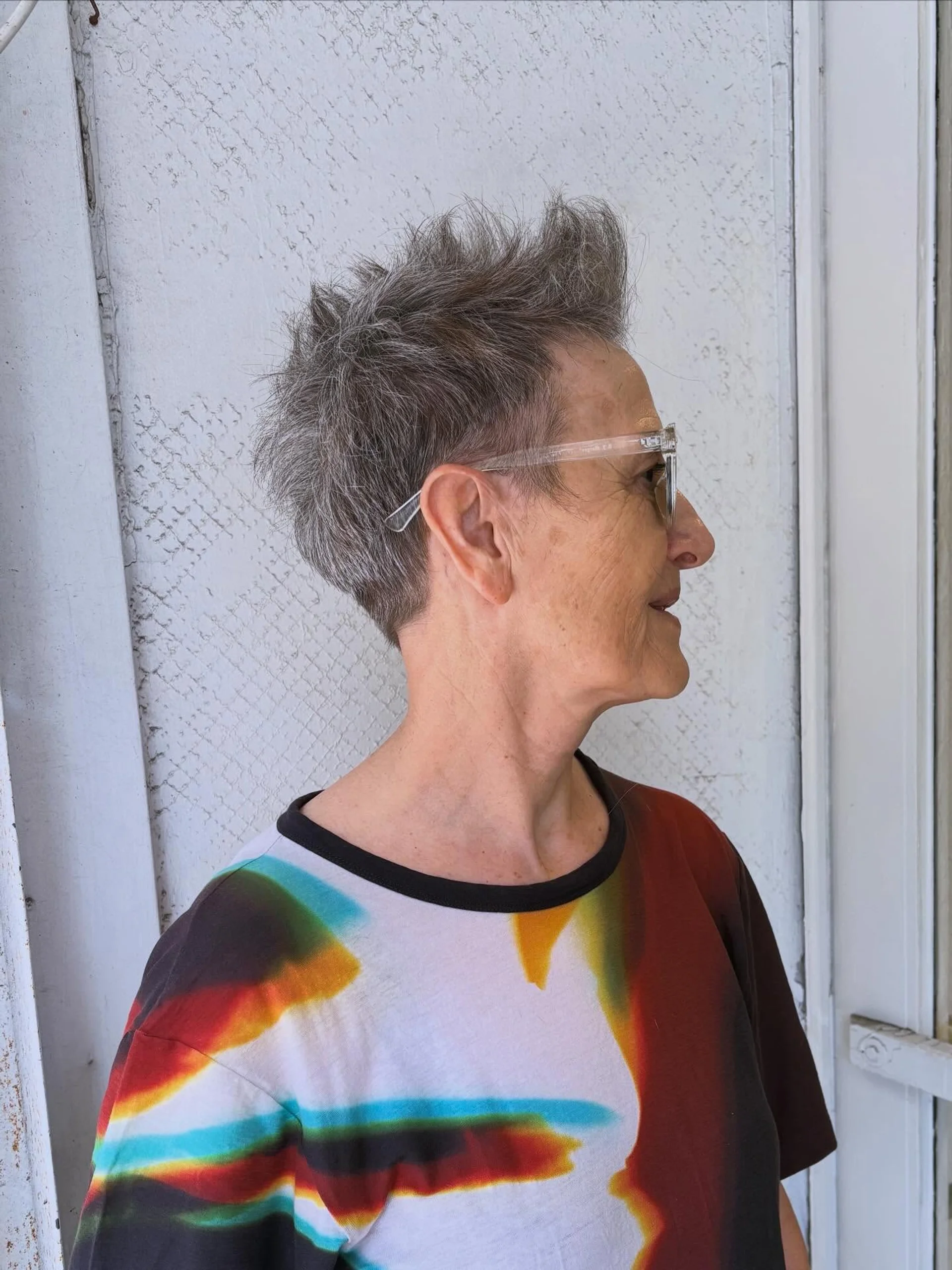 A person with an edgy pixie bob haircut featuring short bangs and choppy layers, seen from the side. - Preview 3