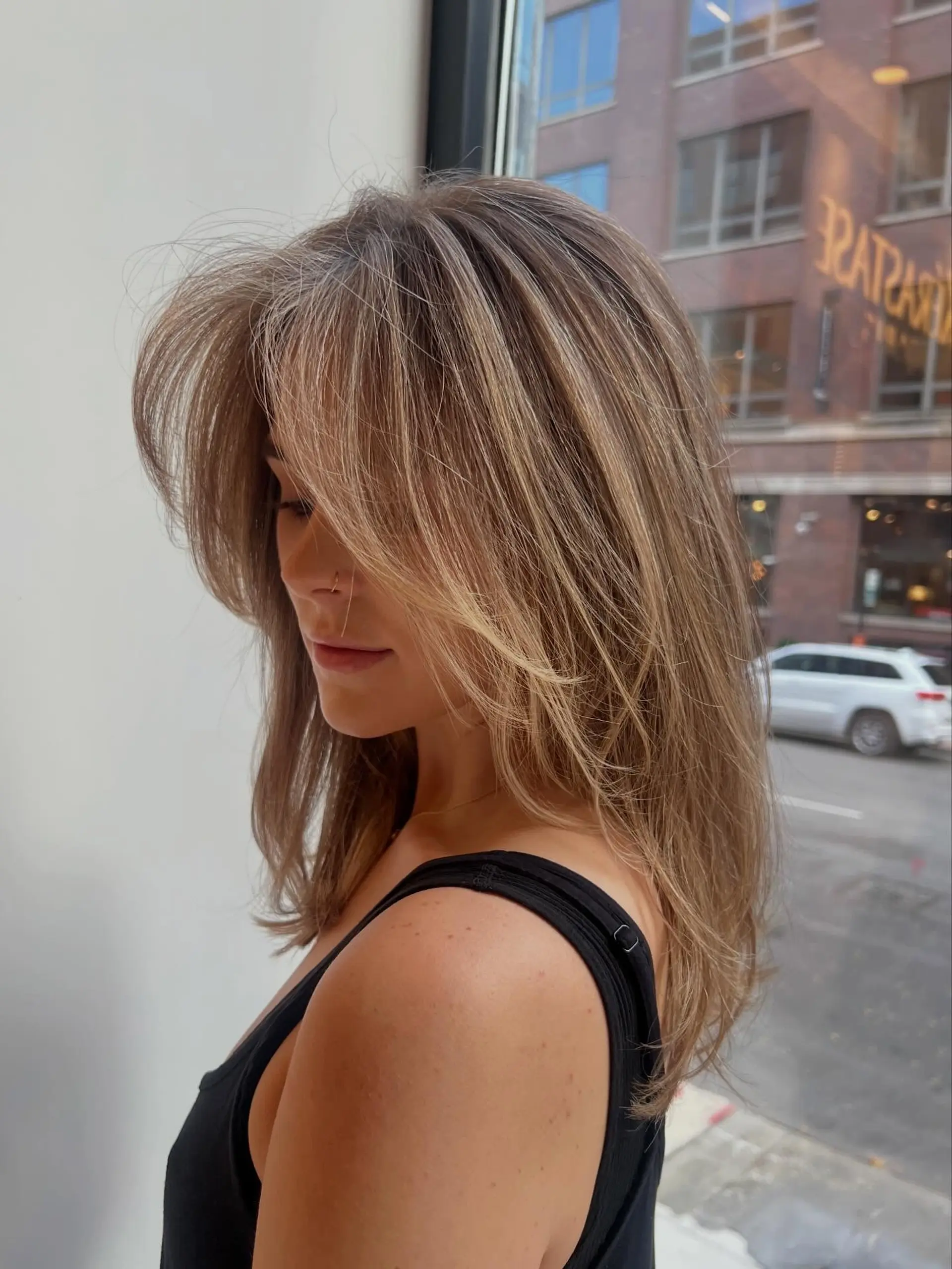 Long layered cut featuring seamless dimensional blonde highlights, face-framing curtain bangs, and soft blowout volume. 1