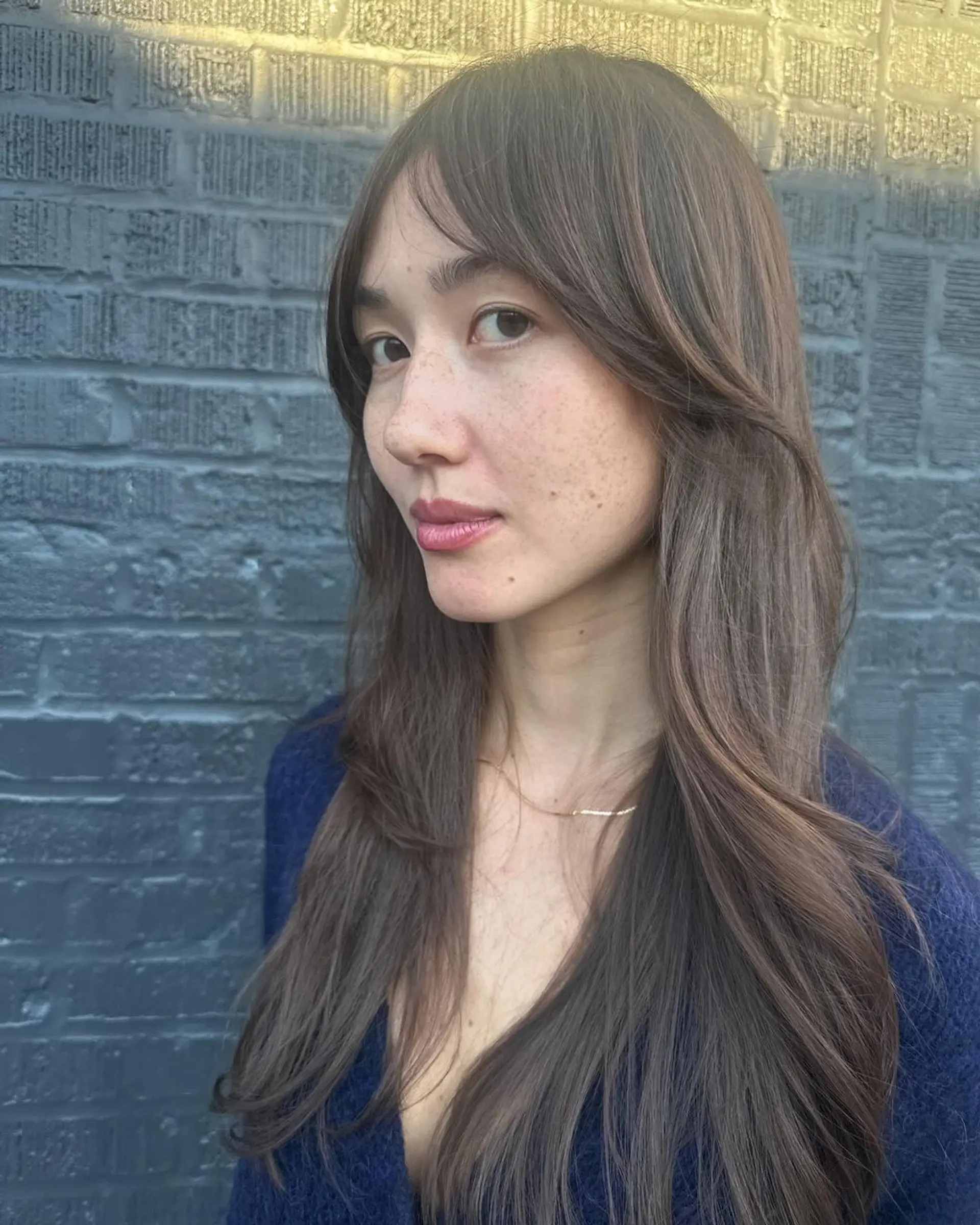 Long, dark brown wavy hair with soft layers, face-framing sections, natural shine, and feathered ends. 1