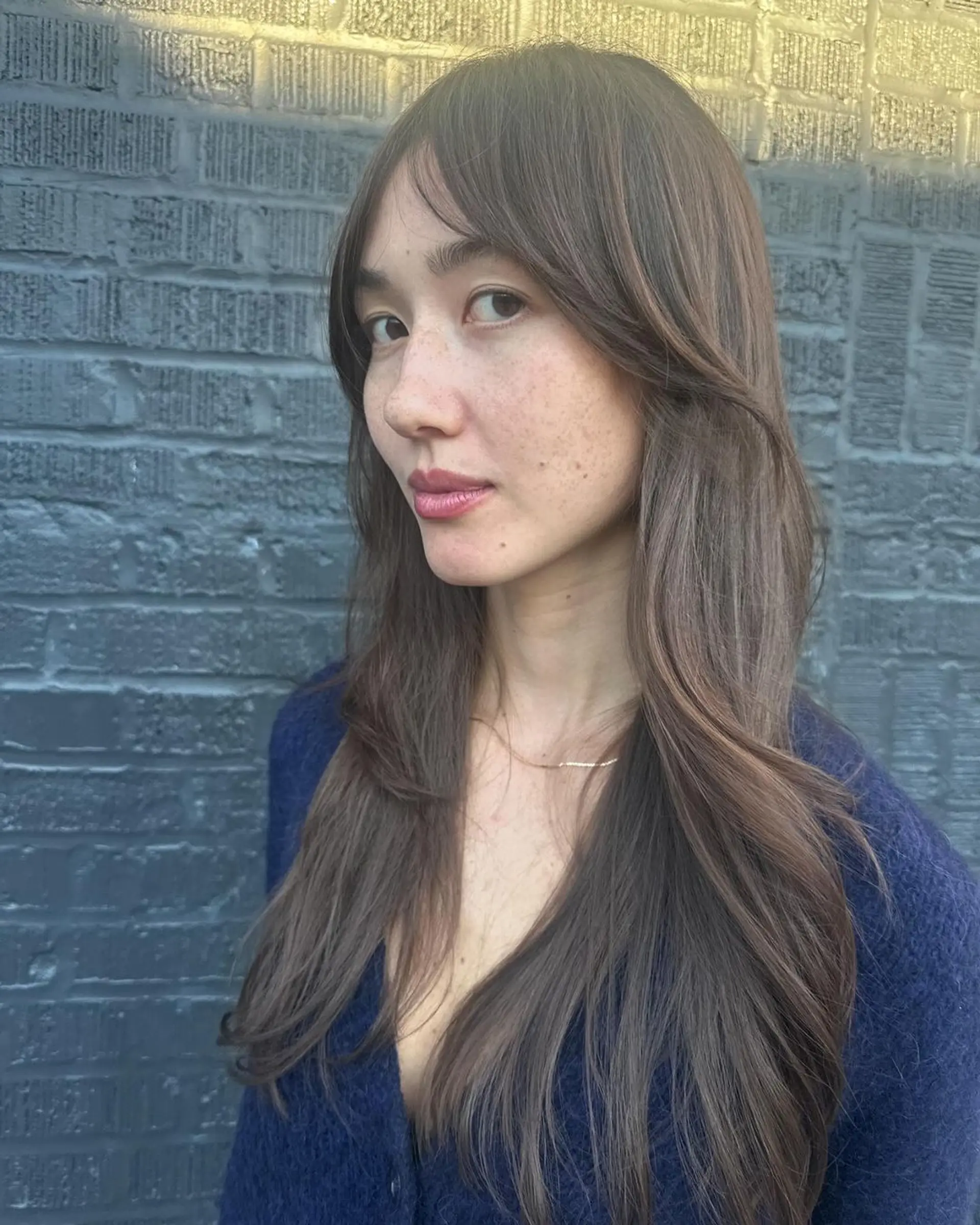 Long, dark brown wavy hair with soft layers, face-framing sections, natural shine, and feathered ends. 3