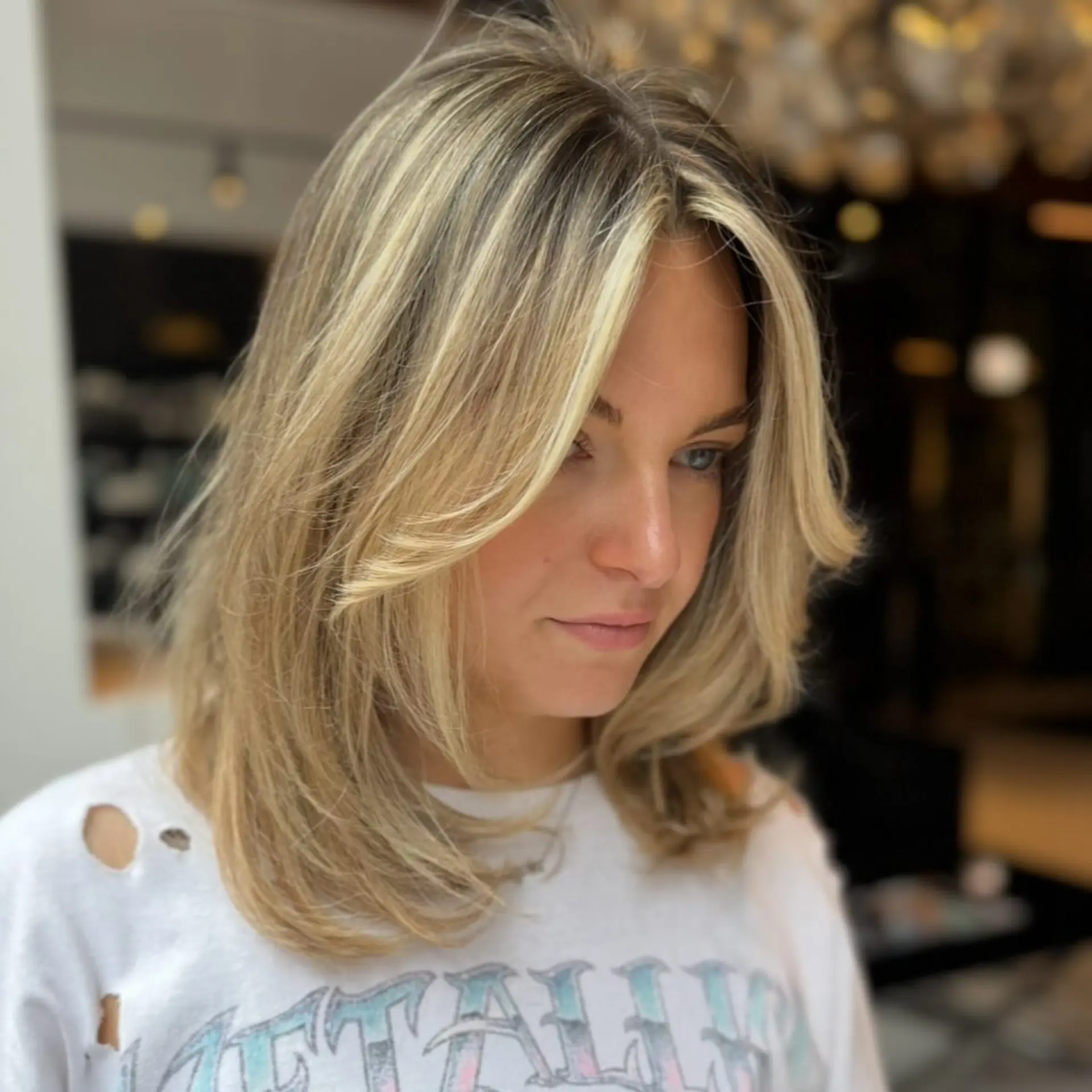 Medium-length layered haircut with face-framing curtain bangs and bright blonde highlights. 1