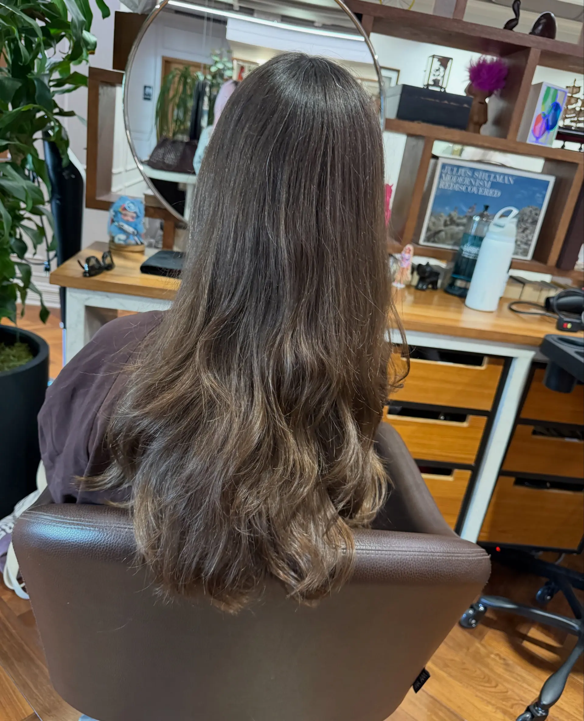 Long brunette hair with subtle dimensional honey highlights and soft loose waves at the ends. 1