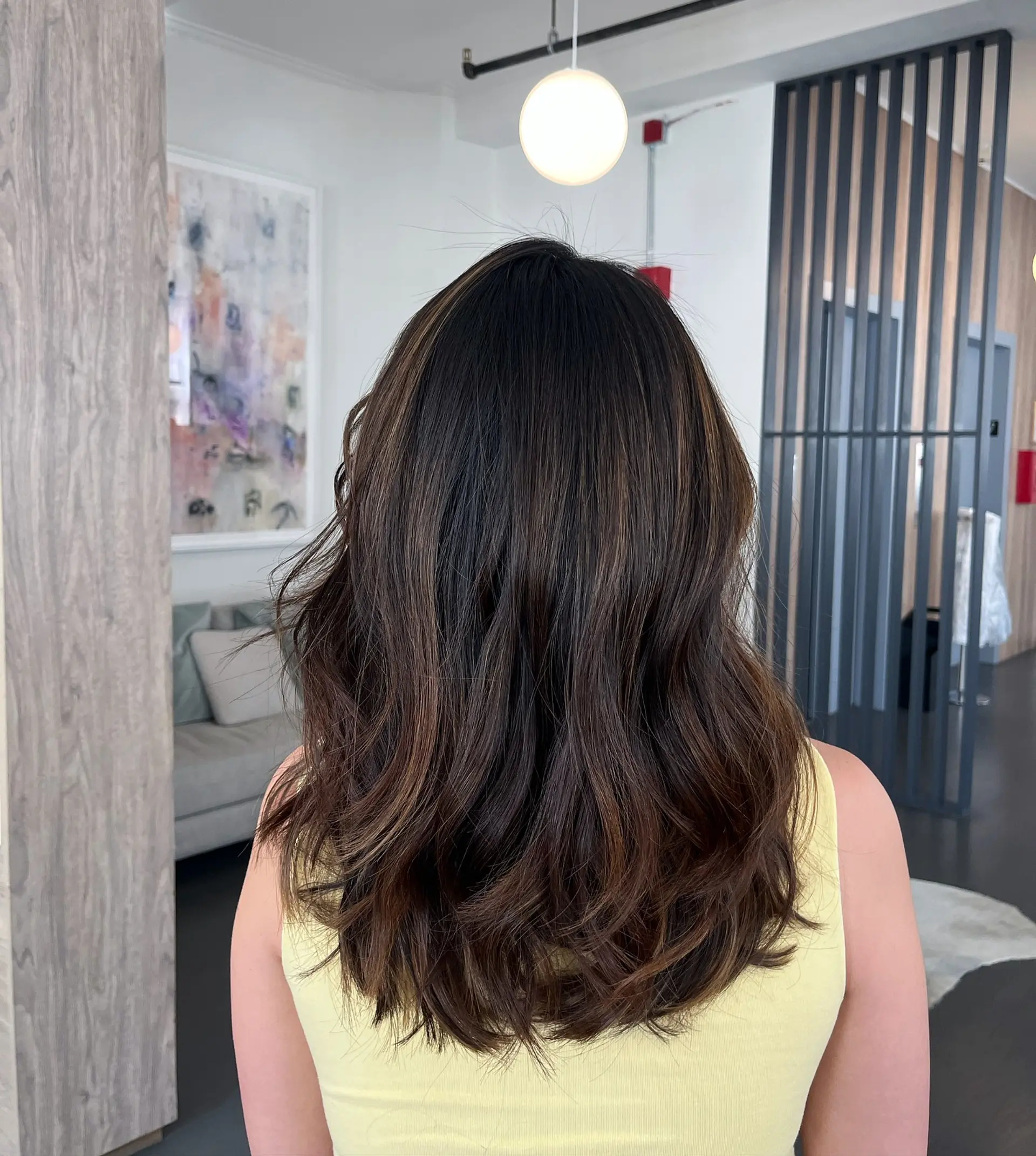 Medium-to-long dark brunette hair featuring subtle, neutral chocolate balayage highlights styled with soft waves. 1
