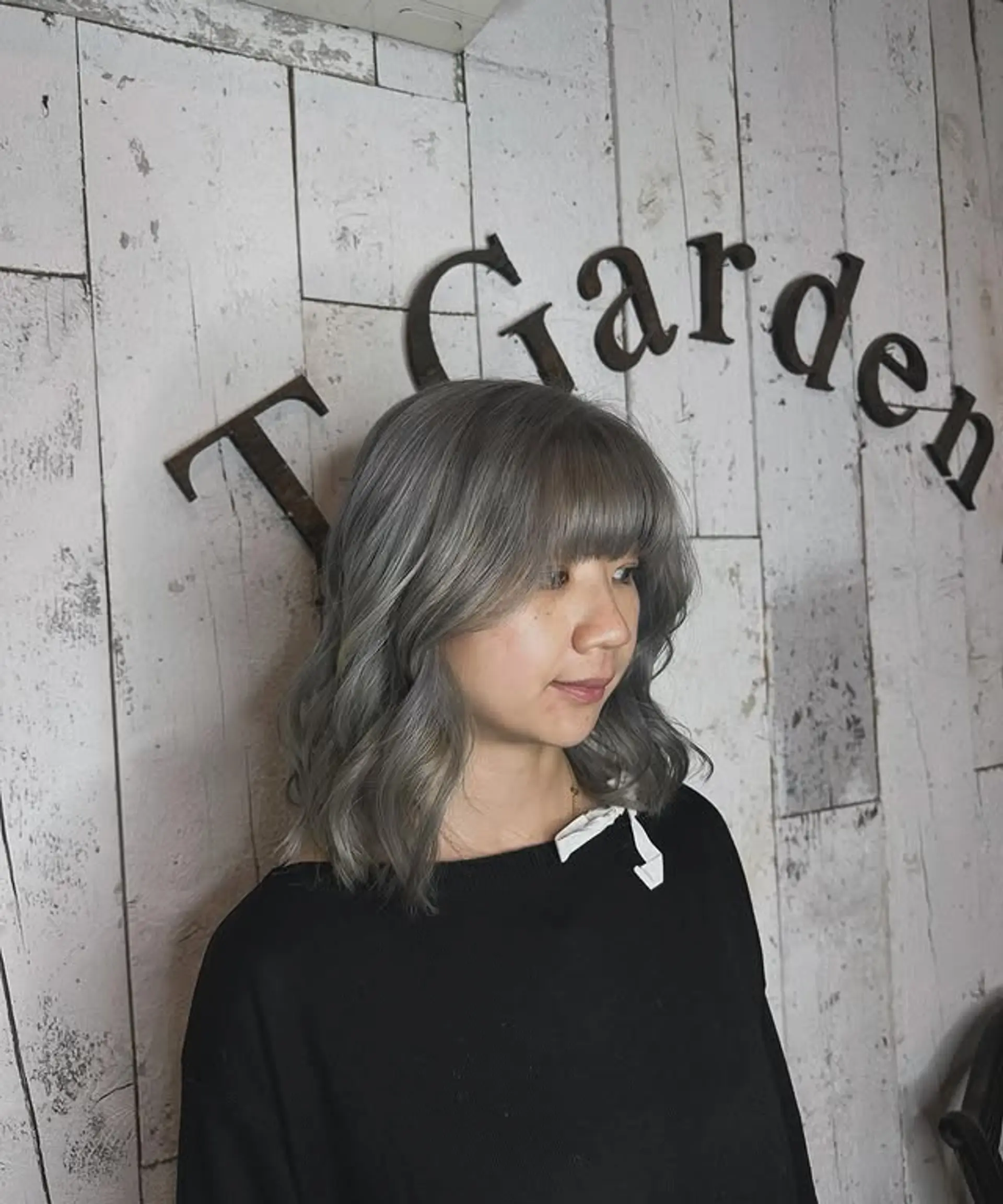A wavy lob with face-framing bangs, styled in a chic ash blonde color. 1
