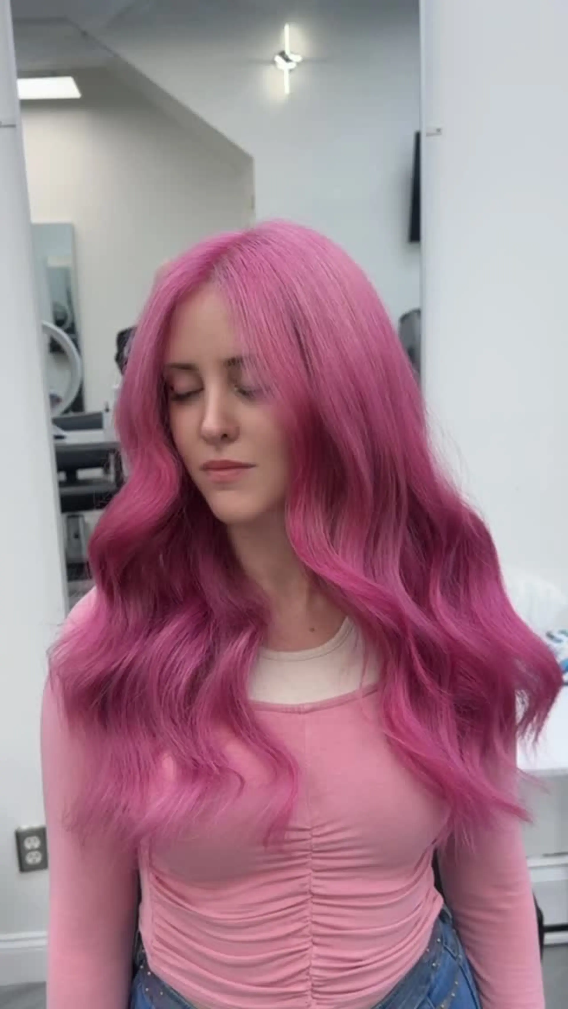 Long vibrant pink hair styled with a center part and soft, voluminous loose waves. 1