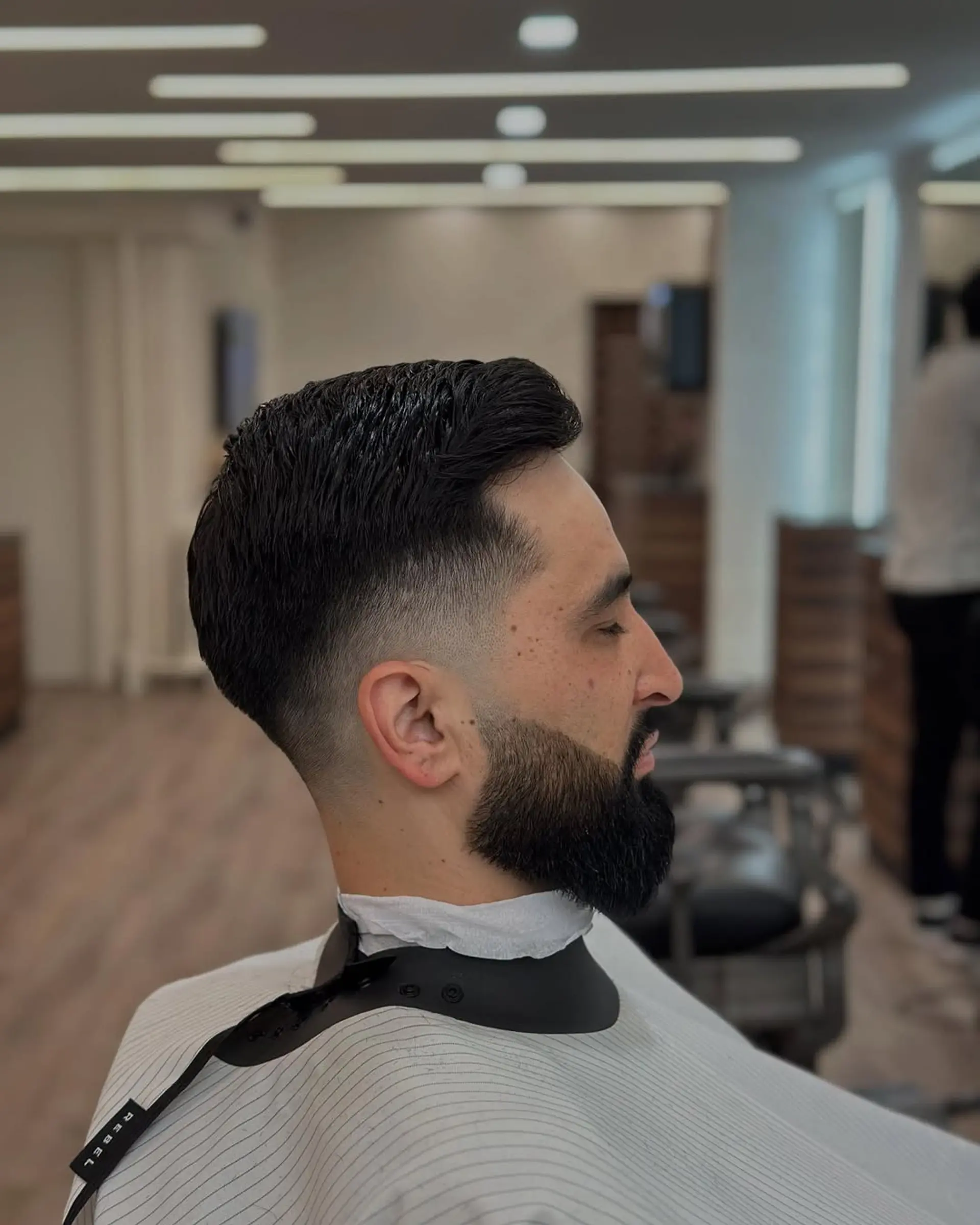 A sleek taper fade on the sides and back transitions smoothly into a textured, medium-length crop on top, styled for a contemporary and clean finish. 1