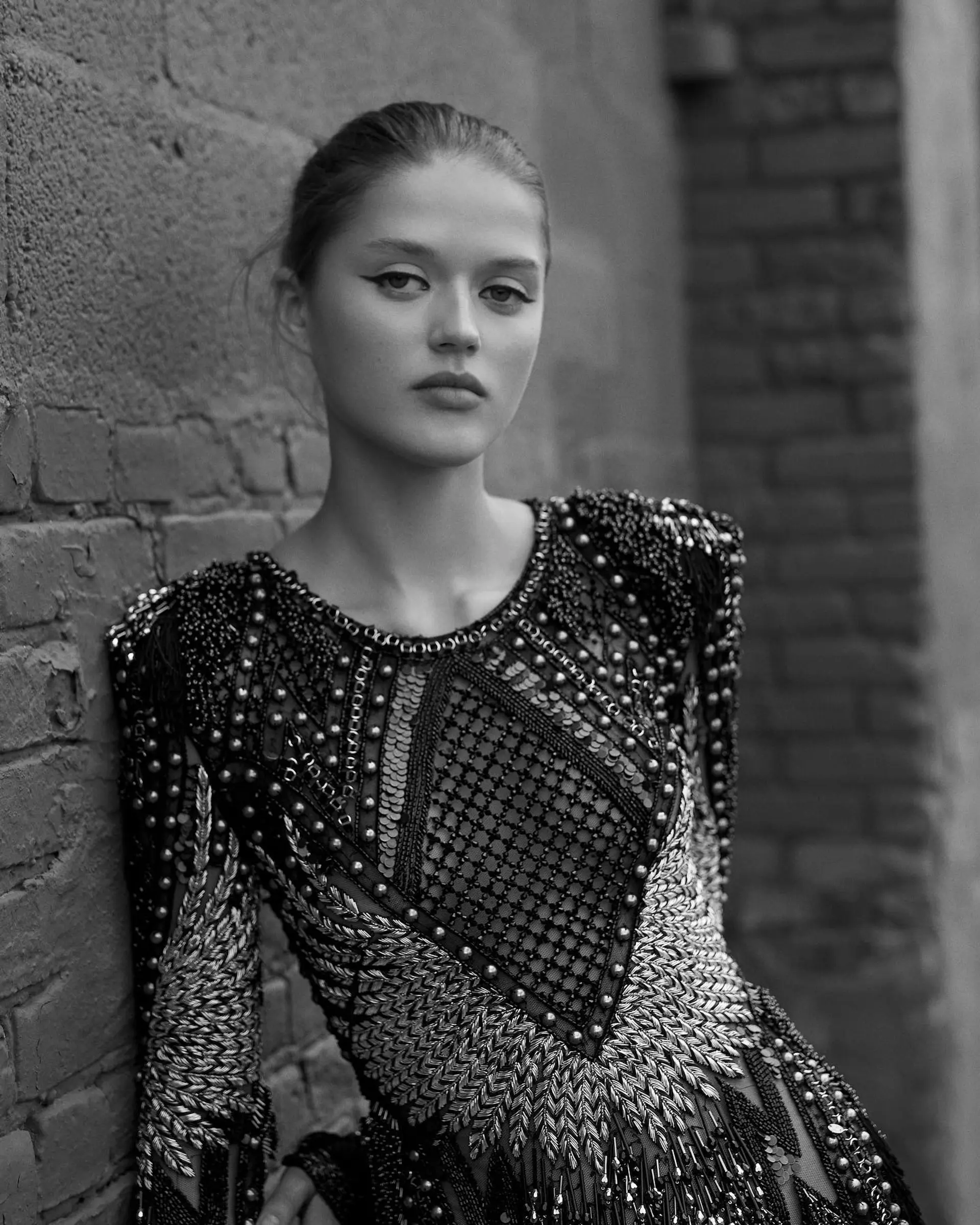 A polished, sleek hairstyle cleanly brushed back away from the hairline into a minimalist updo. 1