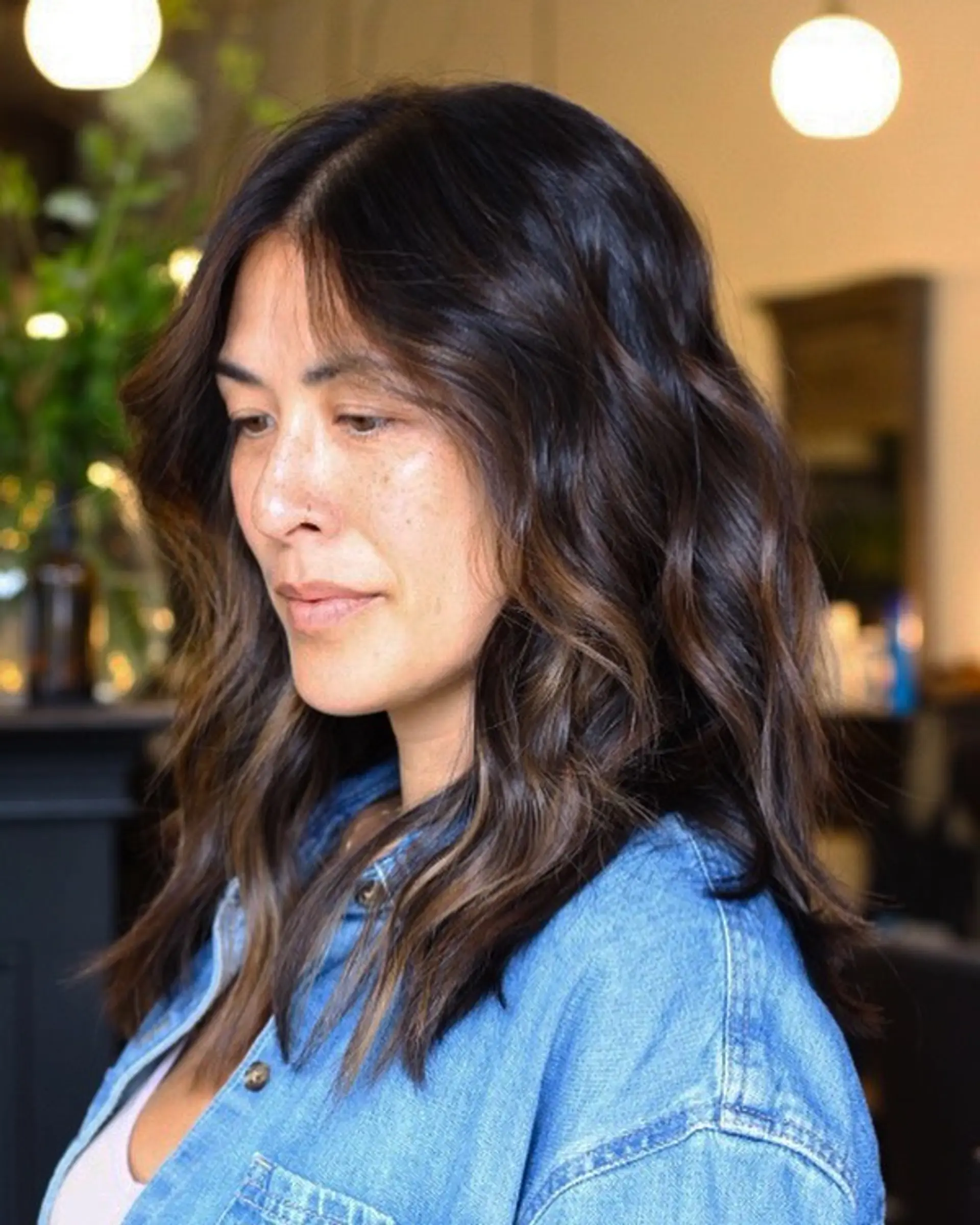 Medium-length dark brown hair featuring subtle warm brown balayage highlights styled in relaxed, loose waves. 1