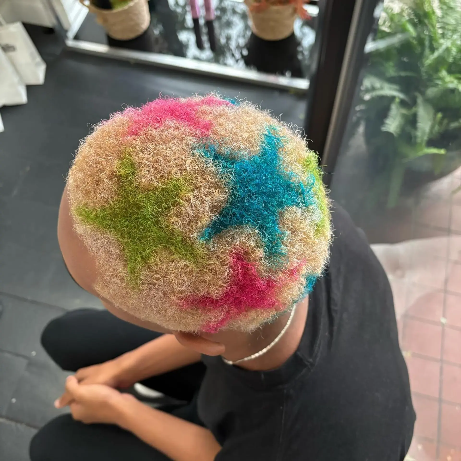 A close blonde buzz cut featuring painted star designs in vibrant blue, pink, and green hues. 1