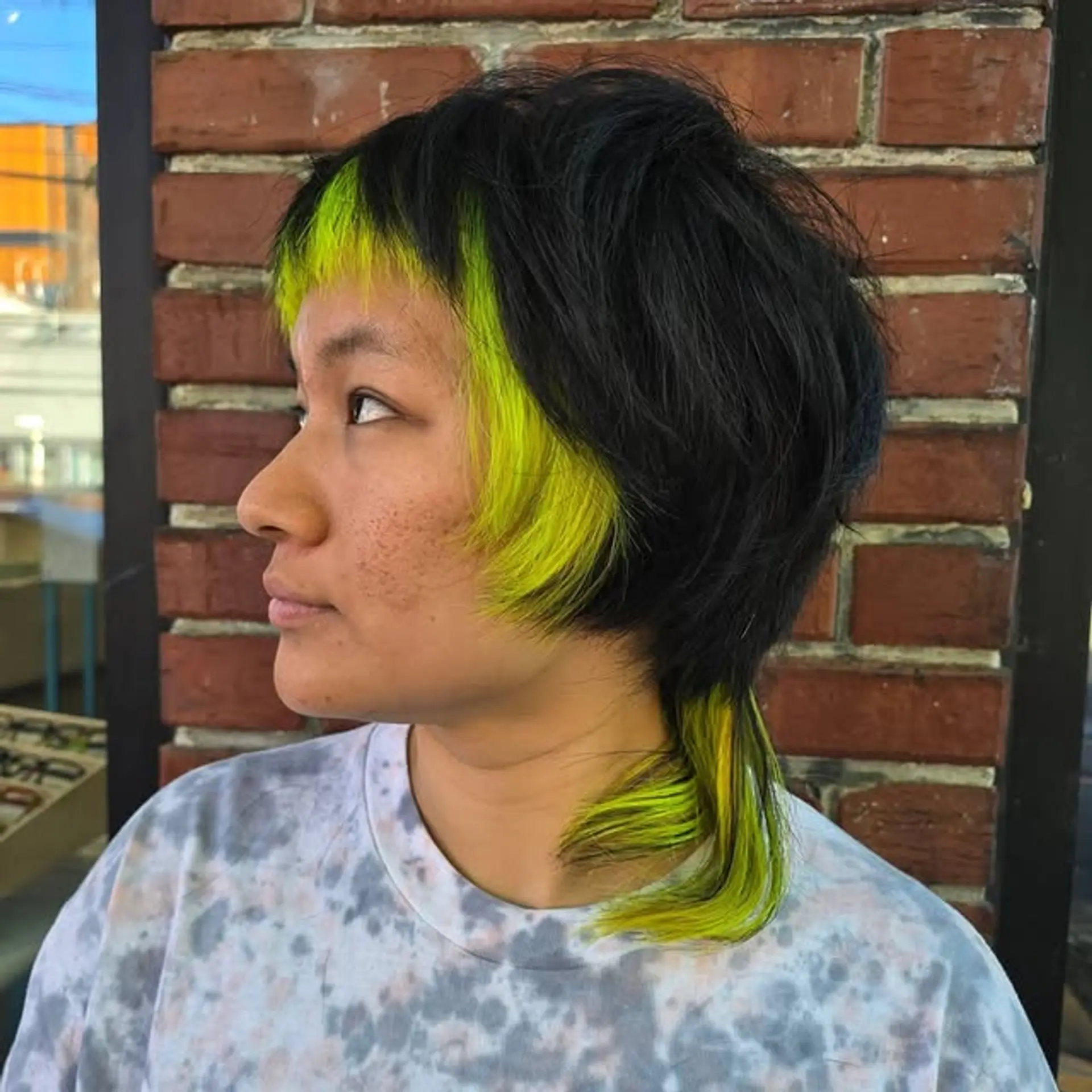 A modern mullet with statement neon yellow money piece highlights and choppy bangs. 1