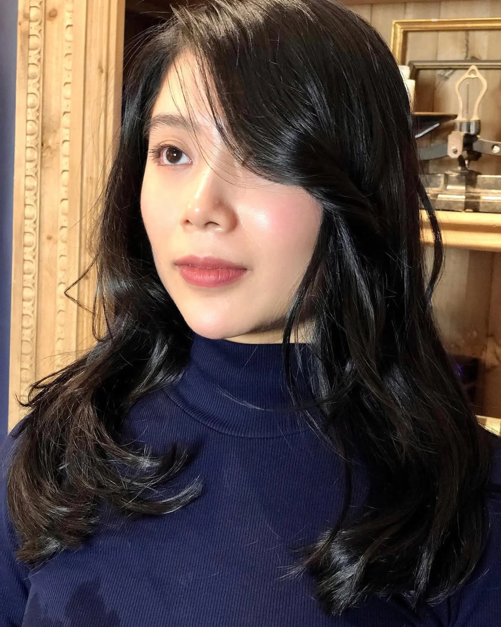 Long, wavy hair with side-swept bangs and a luxuriously shiny finish, featuring soft, natural waves and elegant styling.