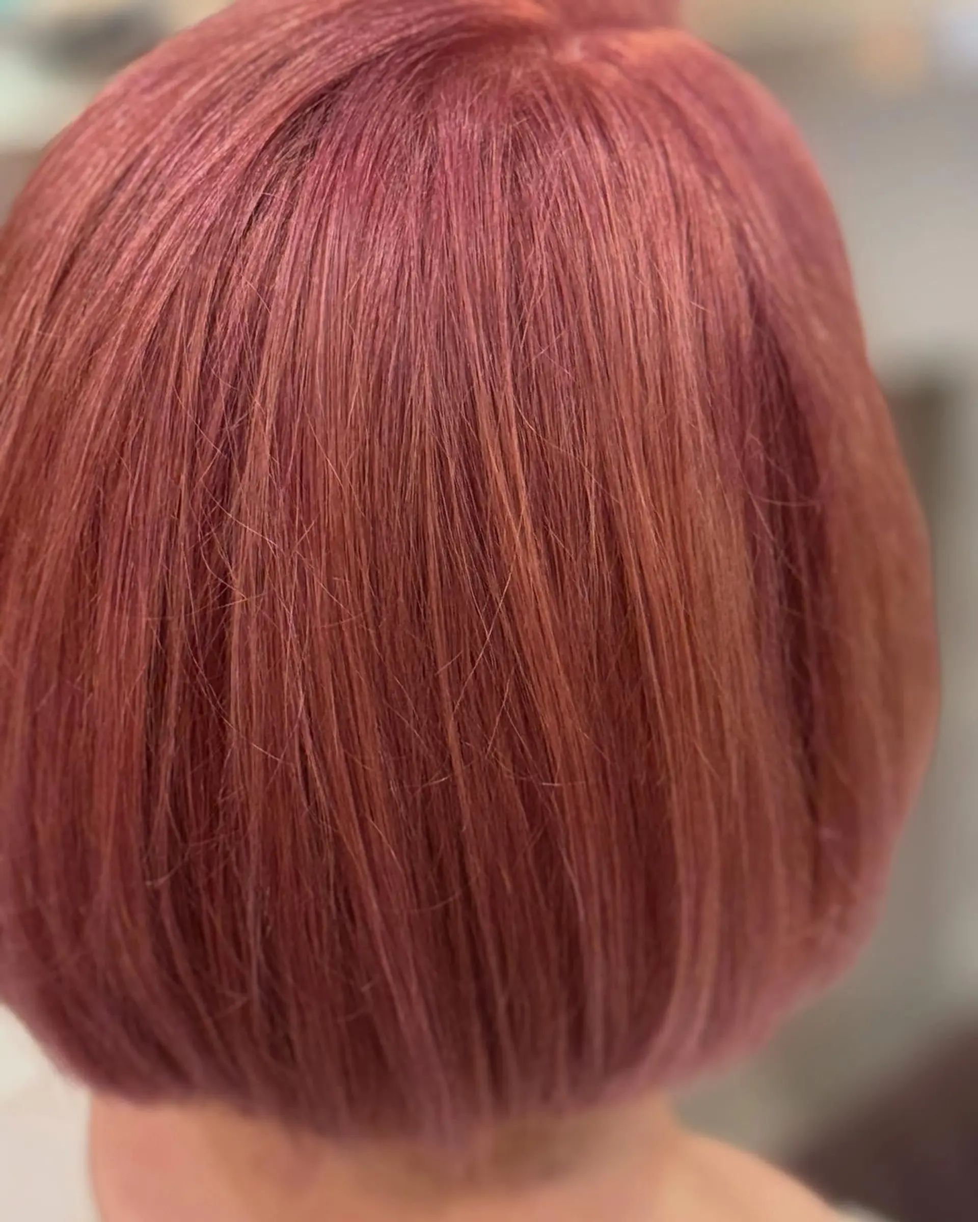 A sleek, one-length short bob haircut featuring a soft dusty rose pink fashion color. 1