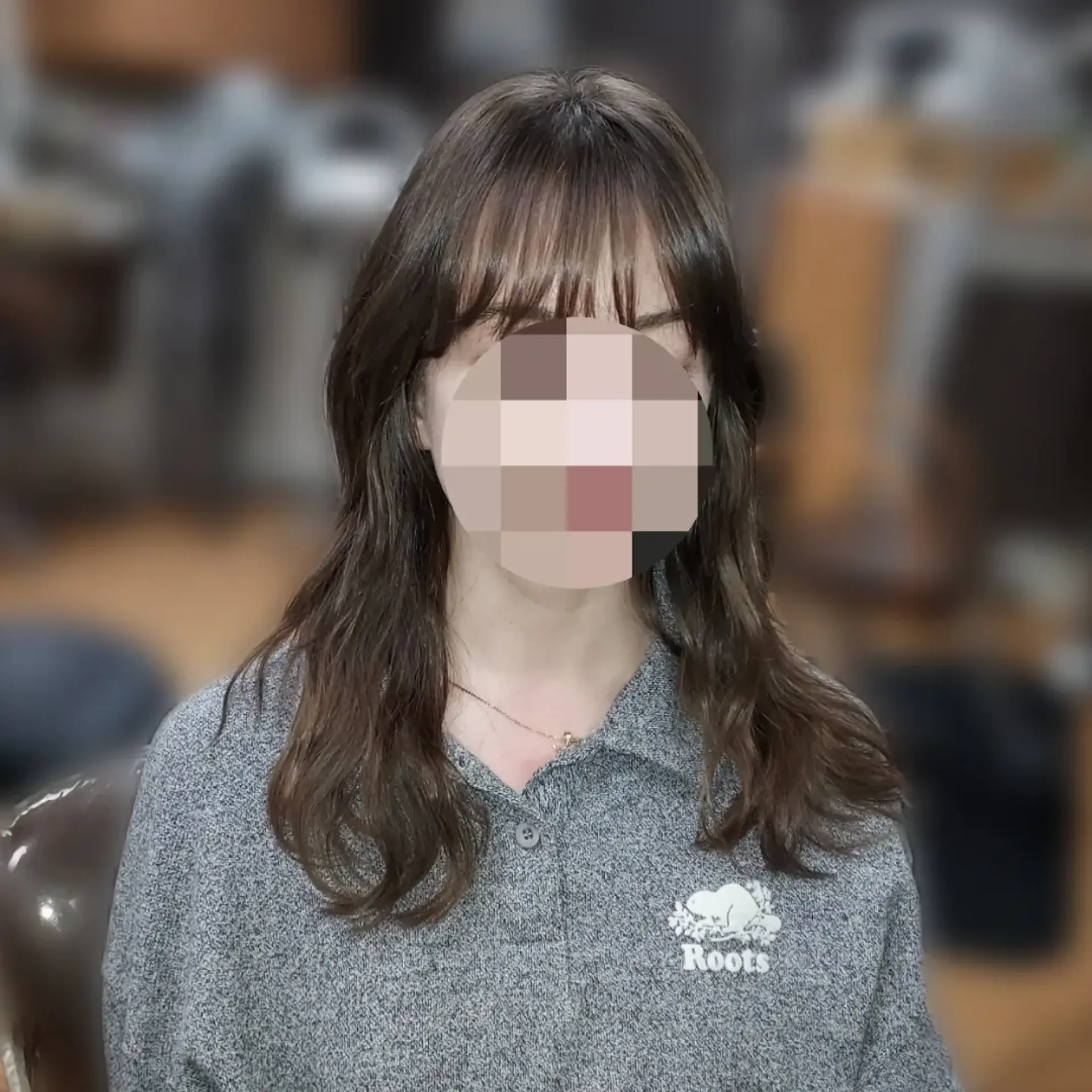 Medium-length layered haircut styled with soft, natural waves at the ends and light, face-framing wispy bangs. 1