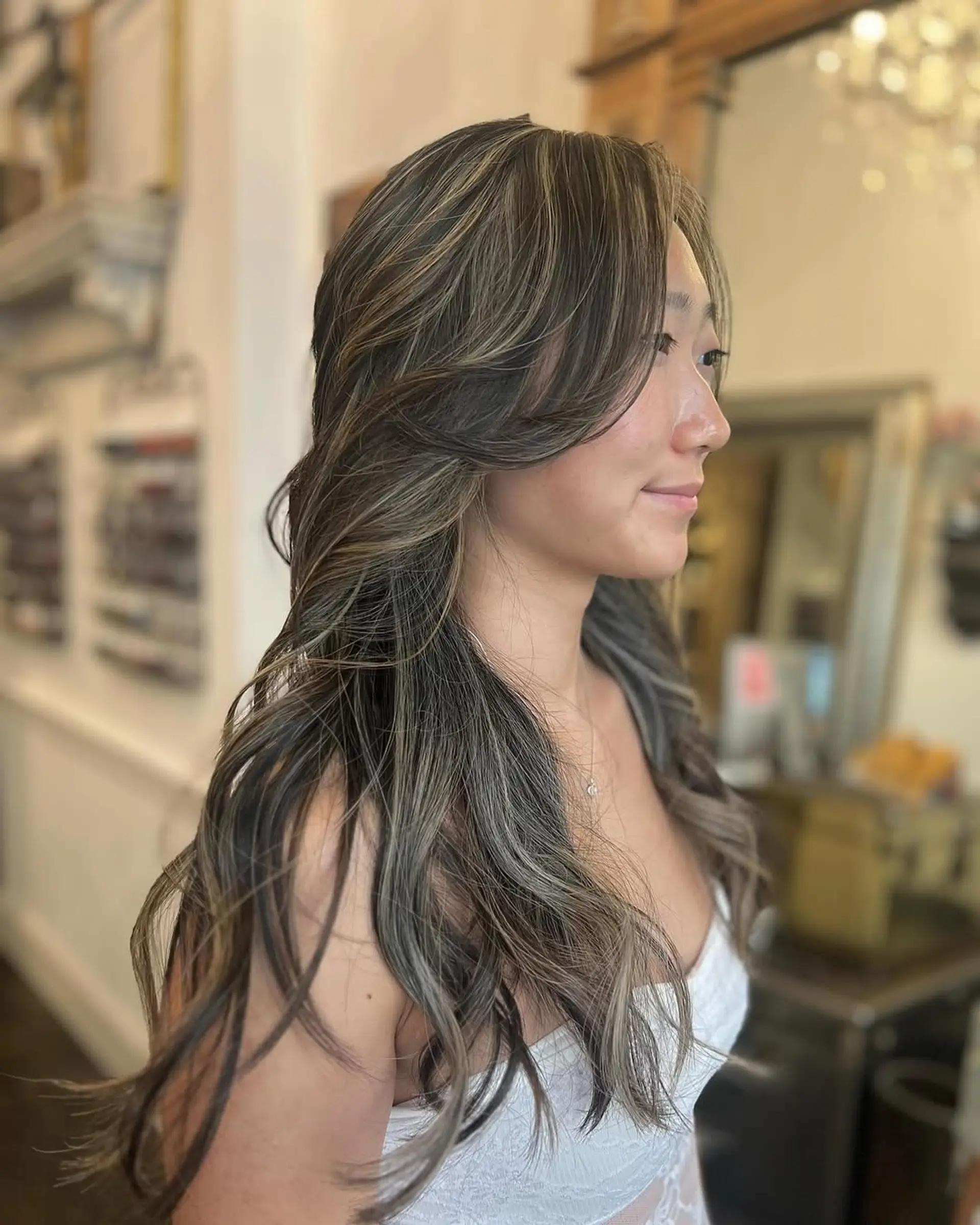 Long, wavy hair with ash blonde highlights on dark brown base, layered for volume with face-framing waves. 2