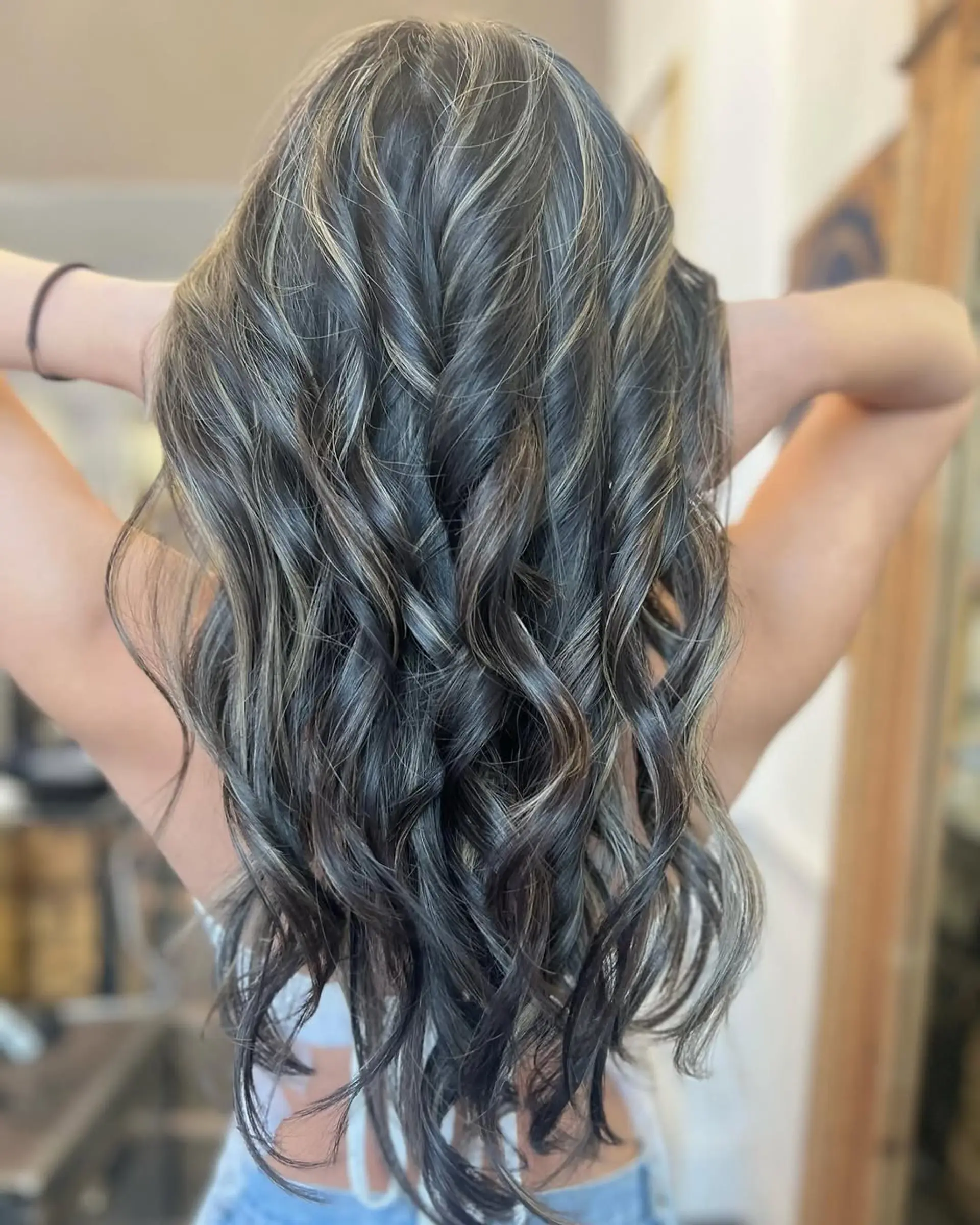 Long, wavy hair with ash blonde highlights on dark brown base, layered for volume with face-framing waves. 3