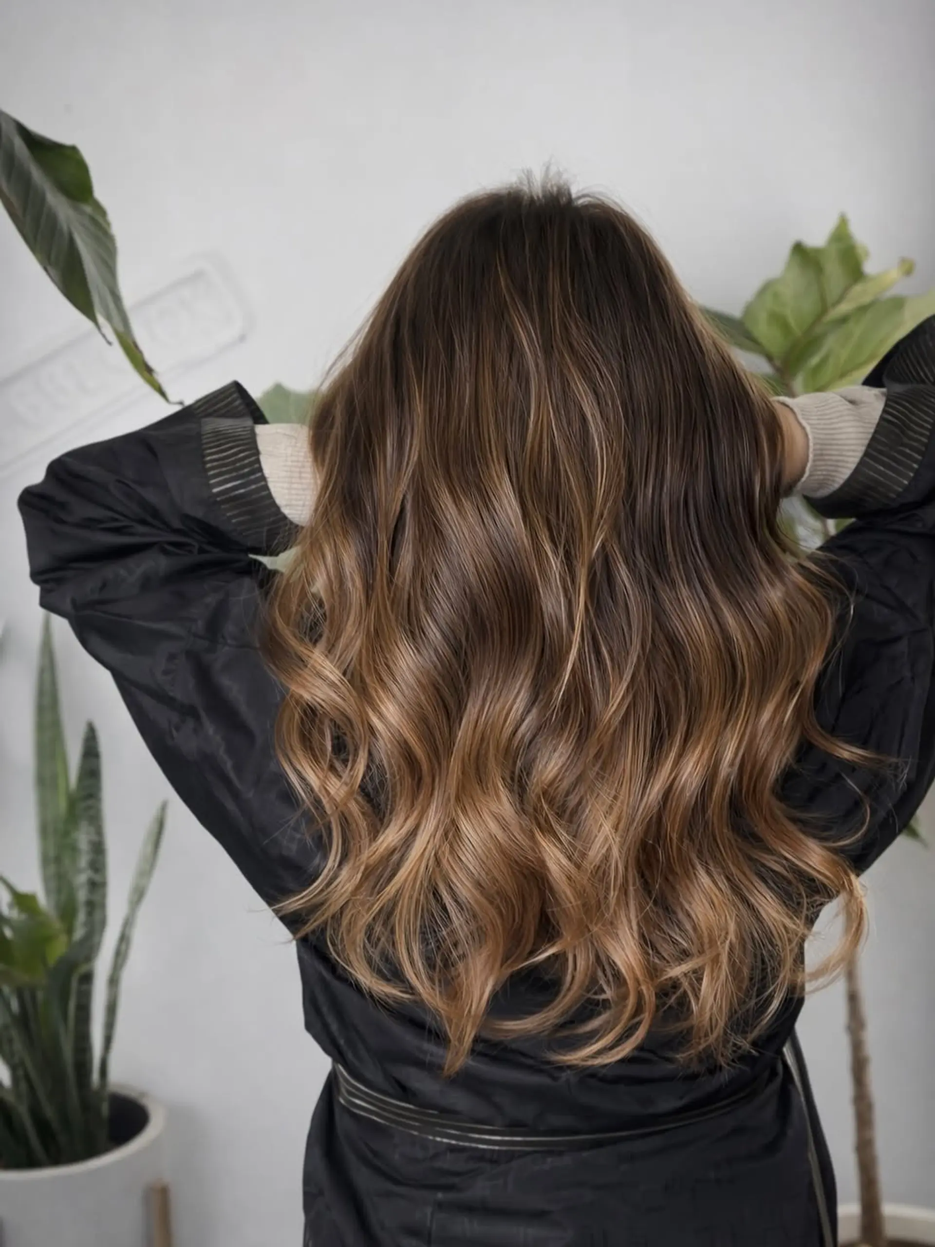 Long hair styled in soft, cascading beachy waves with a dimensional balayage color technique that creates a sun-kissed, gradient effect. 1