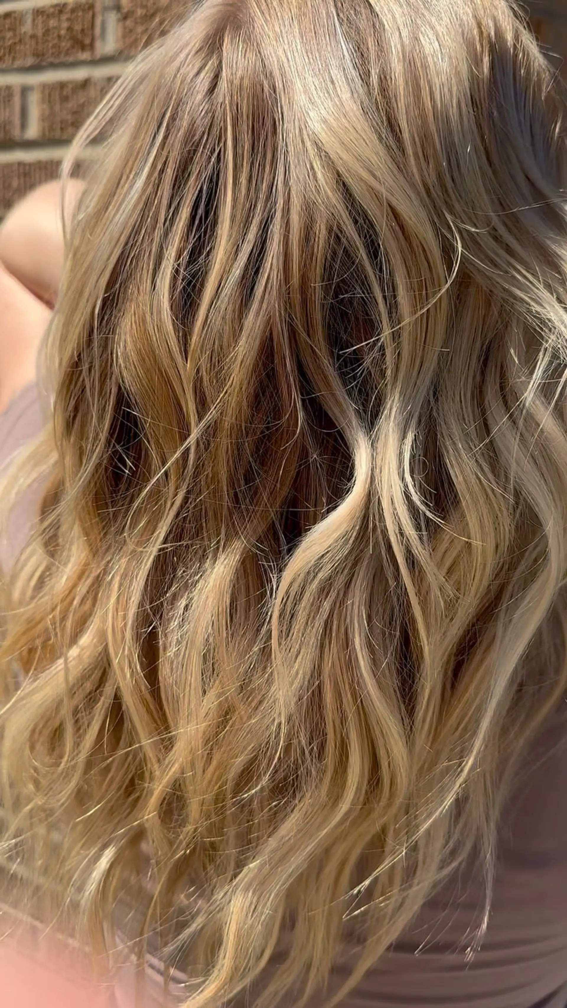 Long dimensional blonde hair styled into effortless textured waves, illuminated under natural sunlight. 1