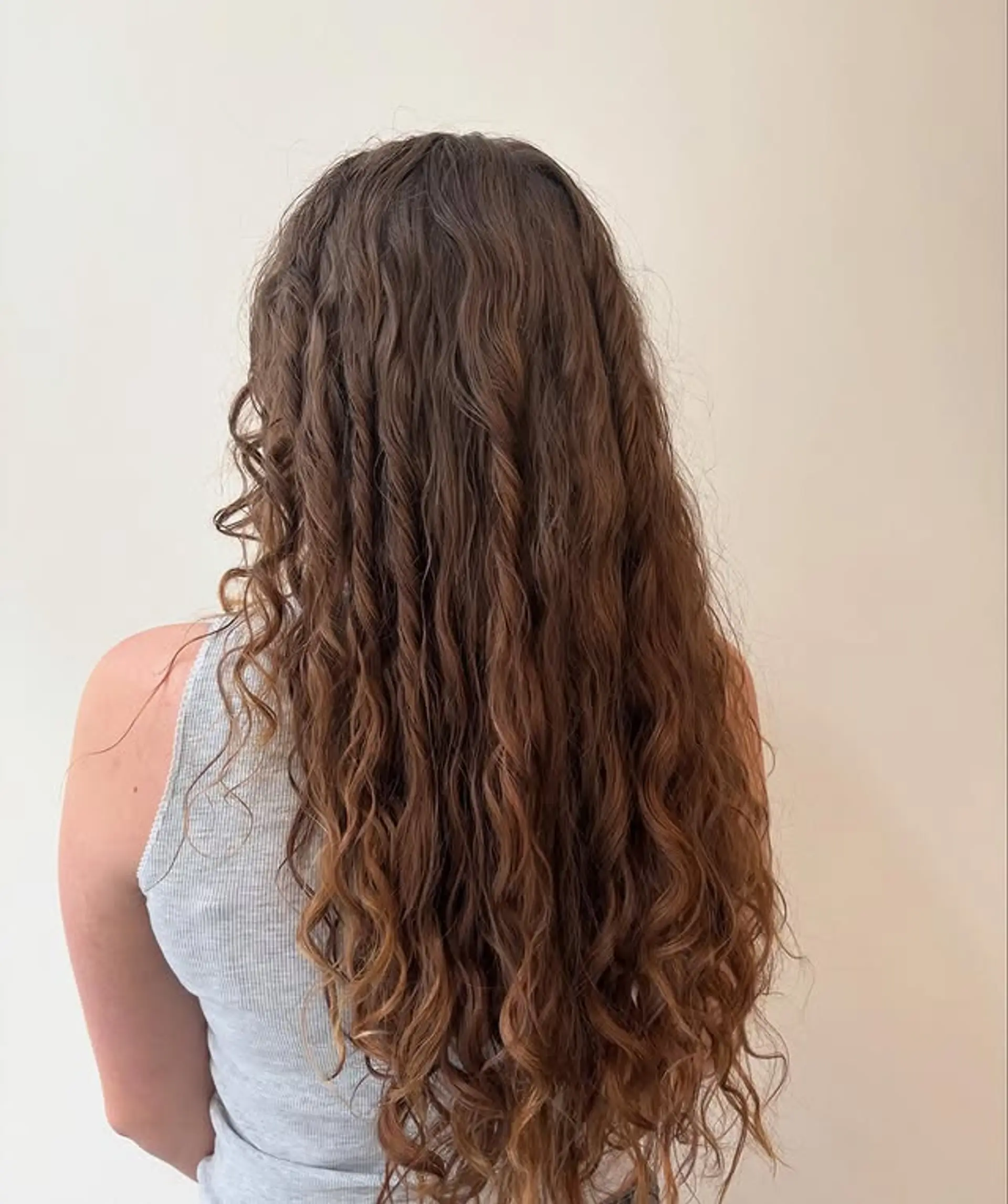 Long layered curly hairstyle with a subtle ombre effect. 1