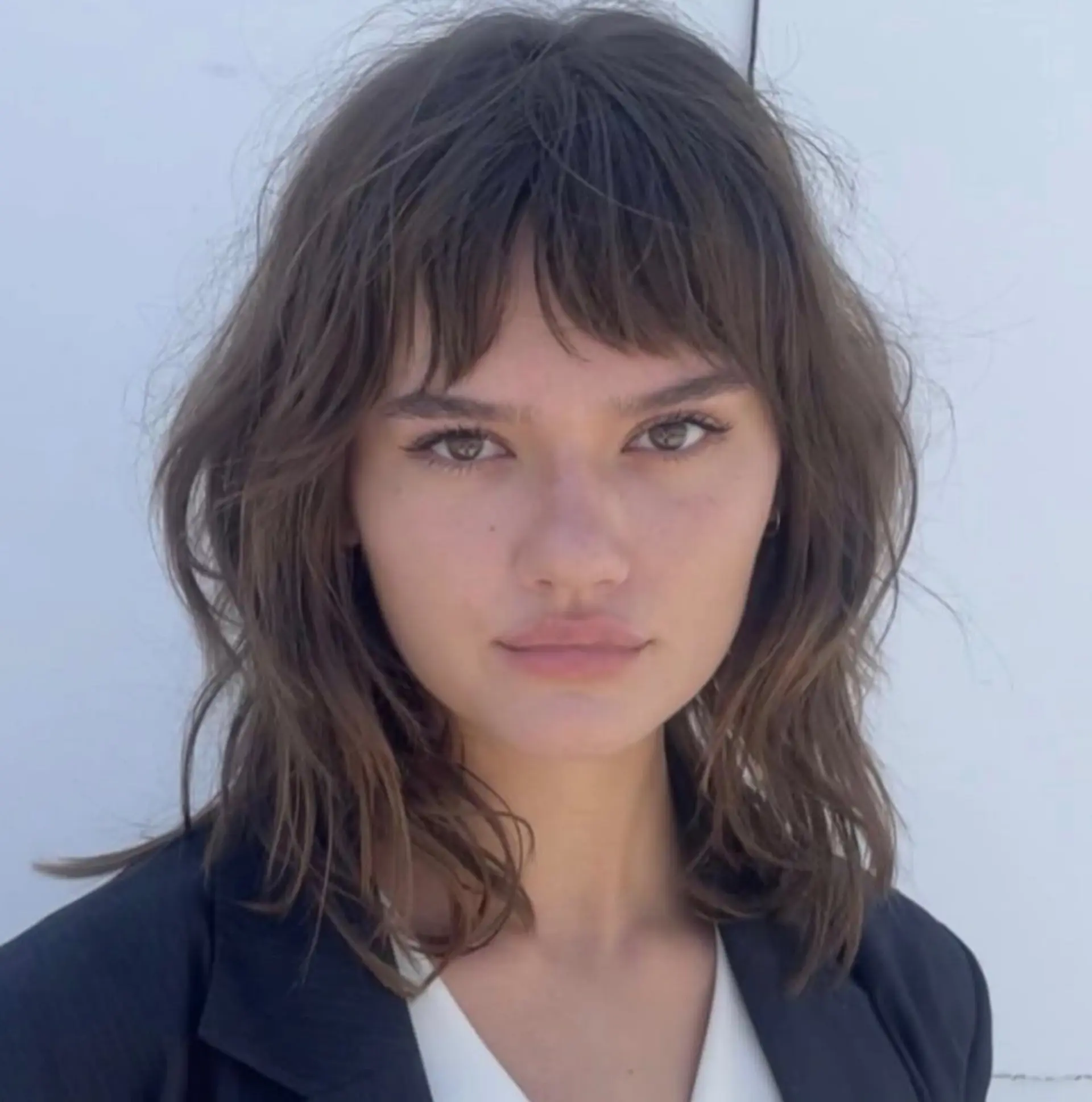 Shoulder-length textured shag haircut featuring choppy micro bangs and soft, face-framing layers. 1