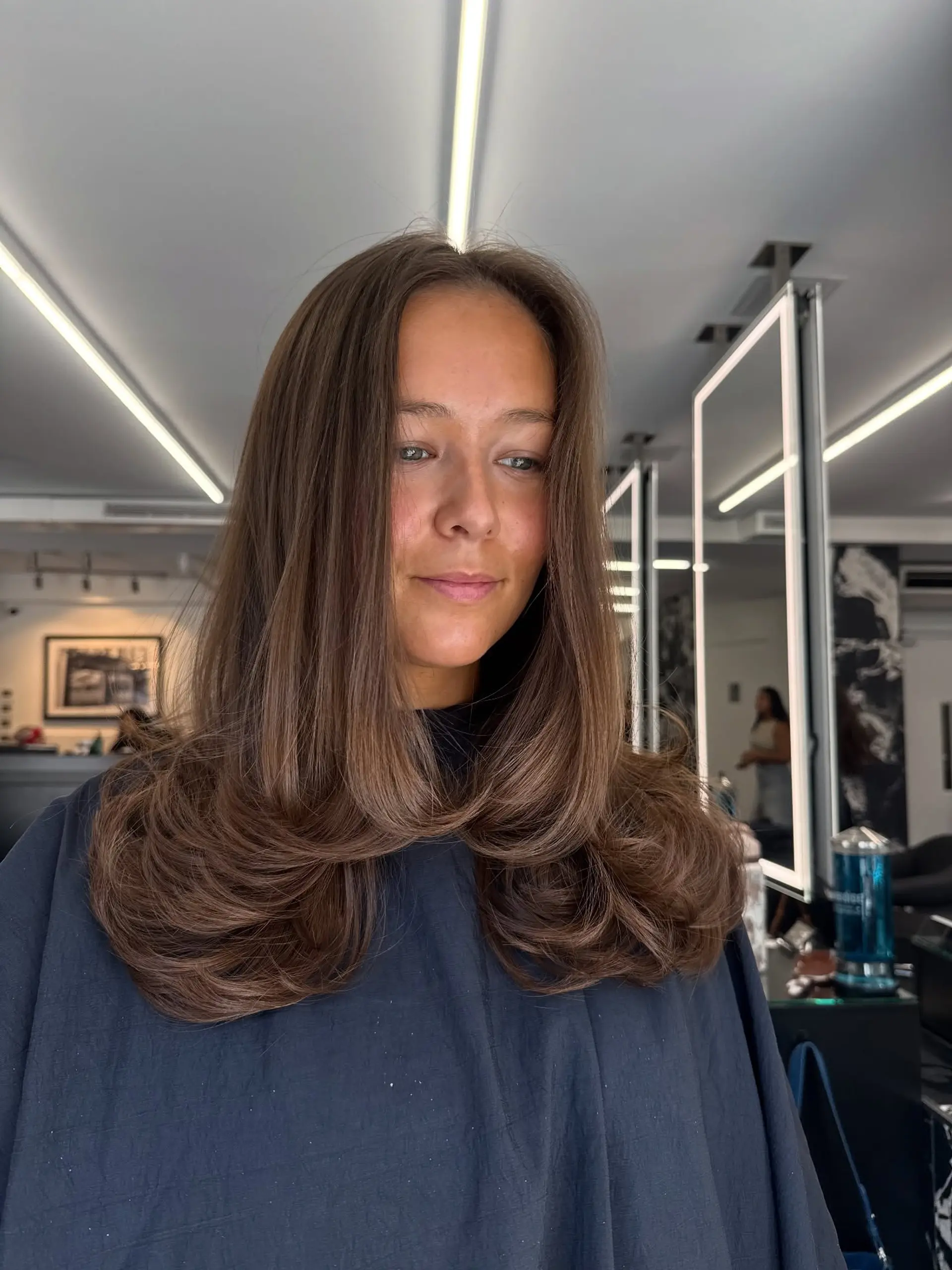 A glossy, long brunette haircut styled into a voluminous blowout with dramatic inward-curled ends. 1