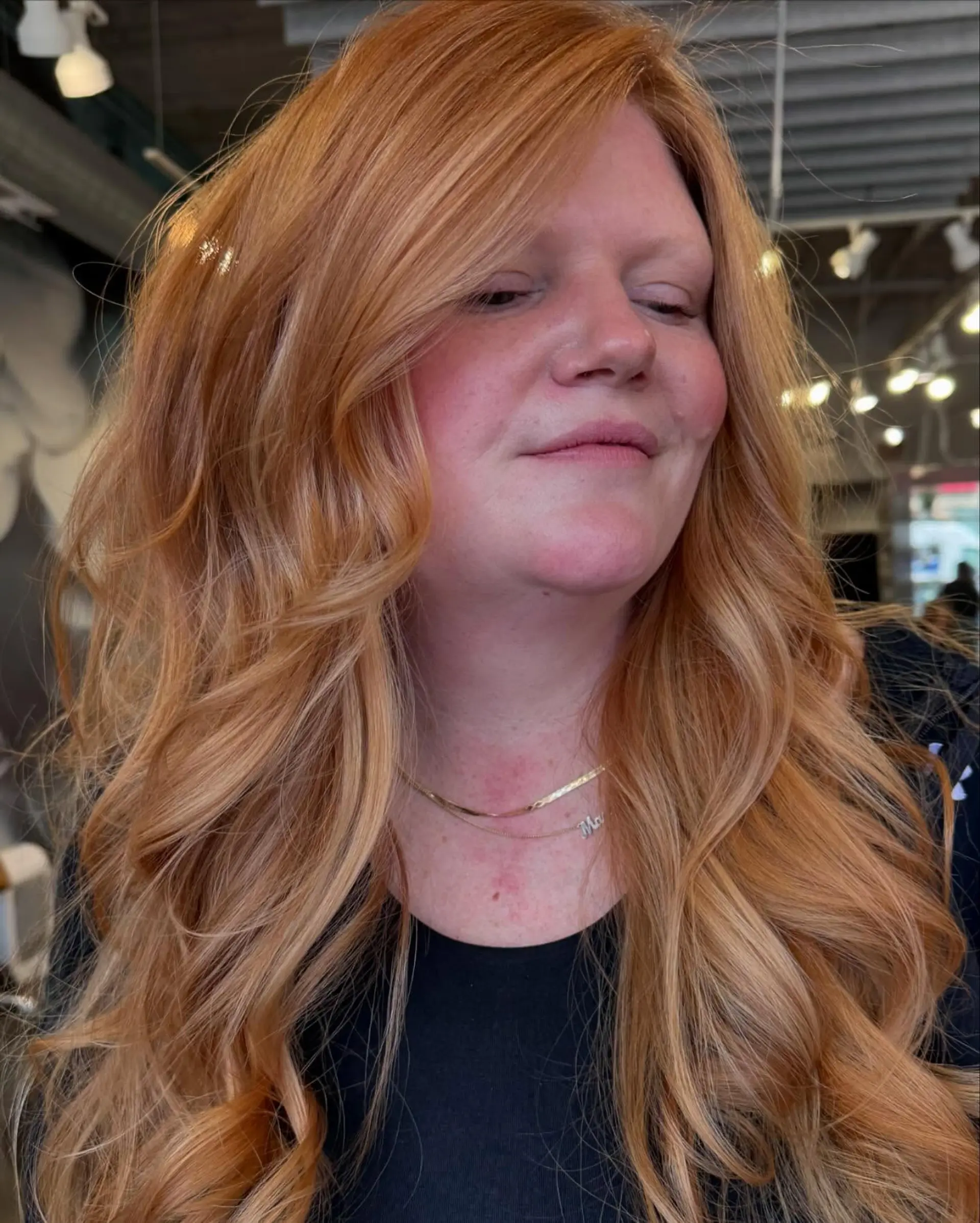 A long, wavy hairstyle with layered ends and face-framing layers, highlighted by a warm copper color with blonde balayage. 2