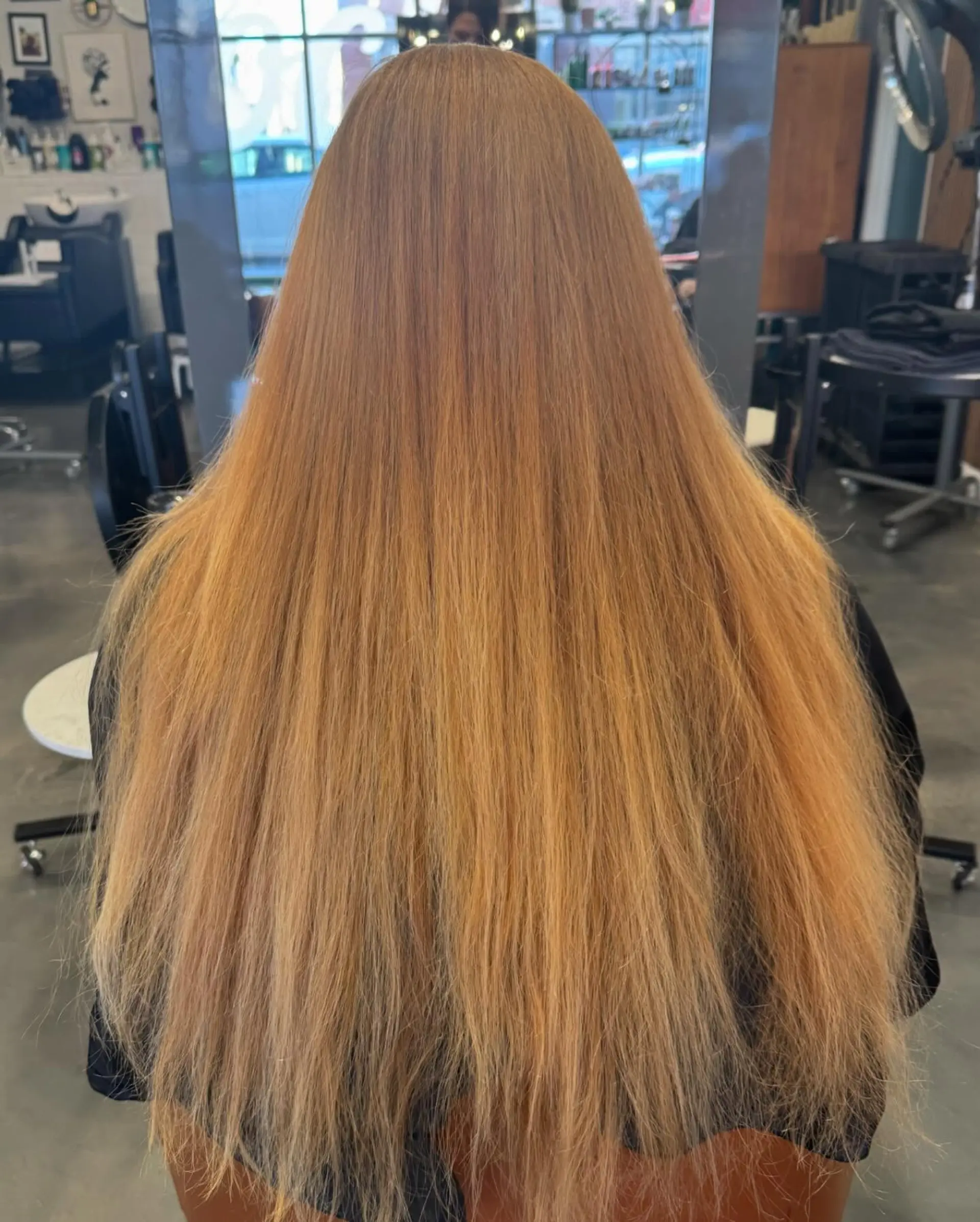 A long, wavy hairstyle with layered ends and face-framing layers, highlighted by a warm copper color with blonde balayage. 4