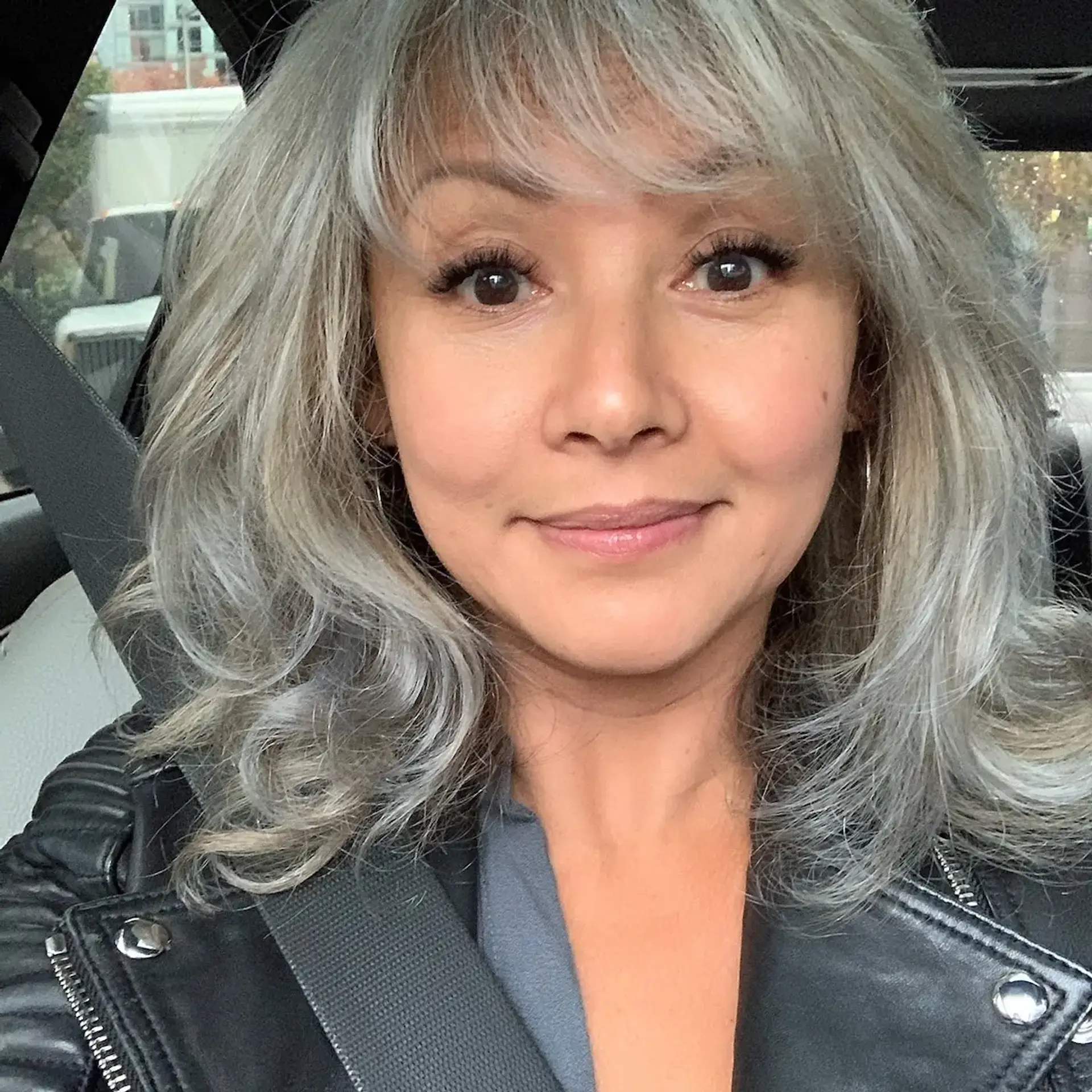 Medium-length layered cut in a luminous silver tone, featuring soft fringe bangs and textured ends. 1