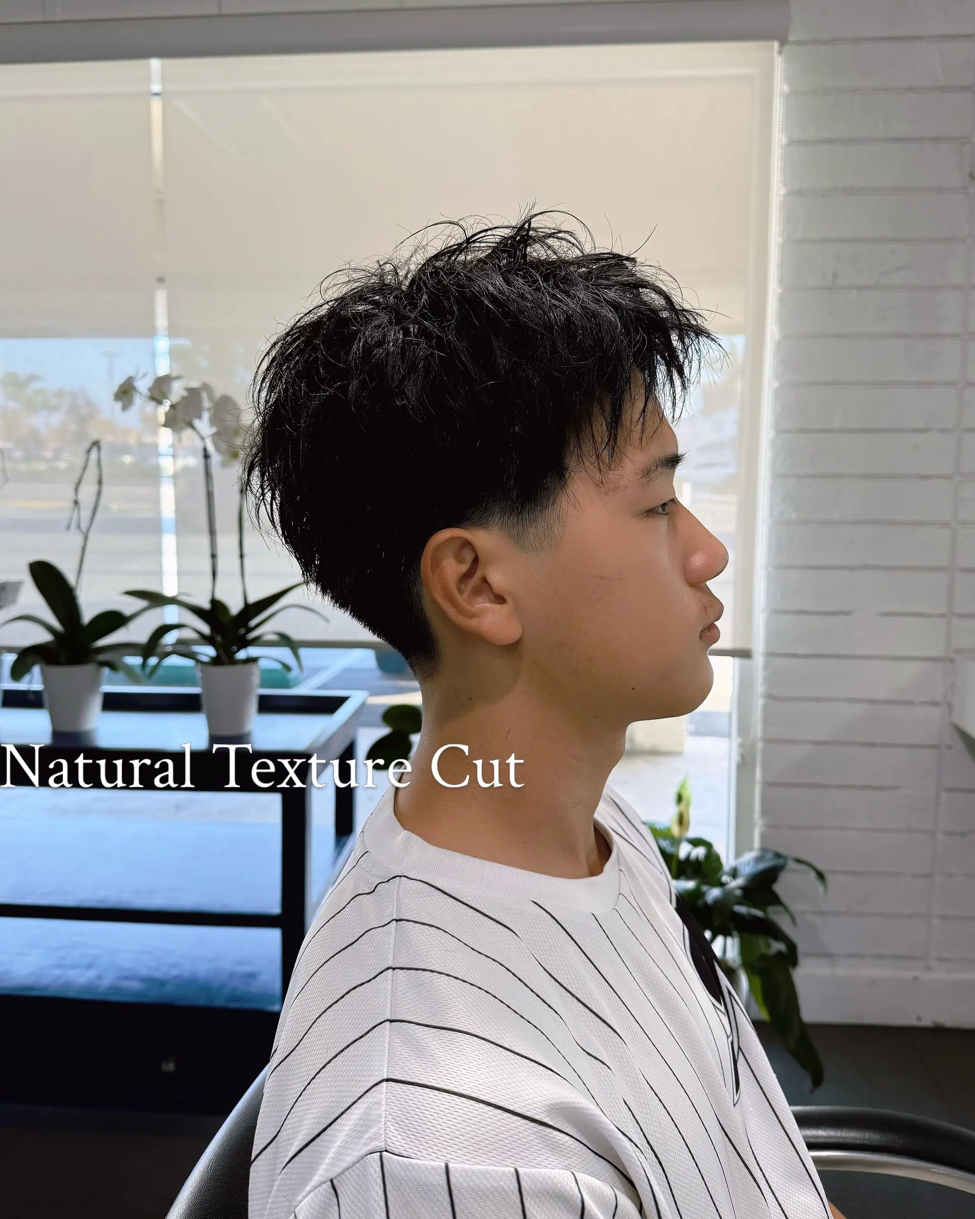A short men's haircut styled to enhance natural movement, featuring textured layers on top and a clean tapered nape. 1