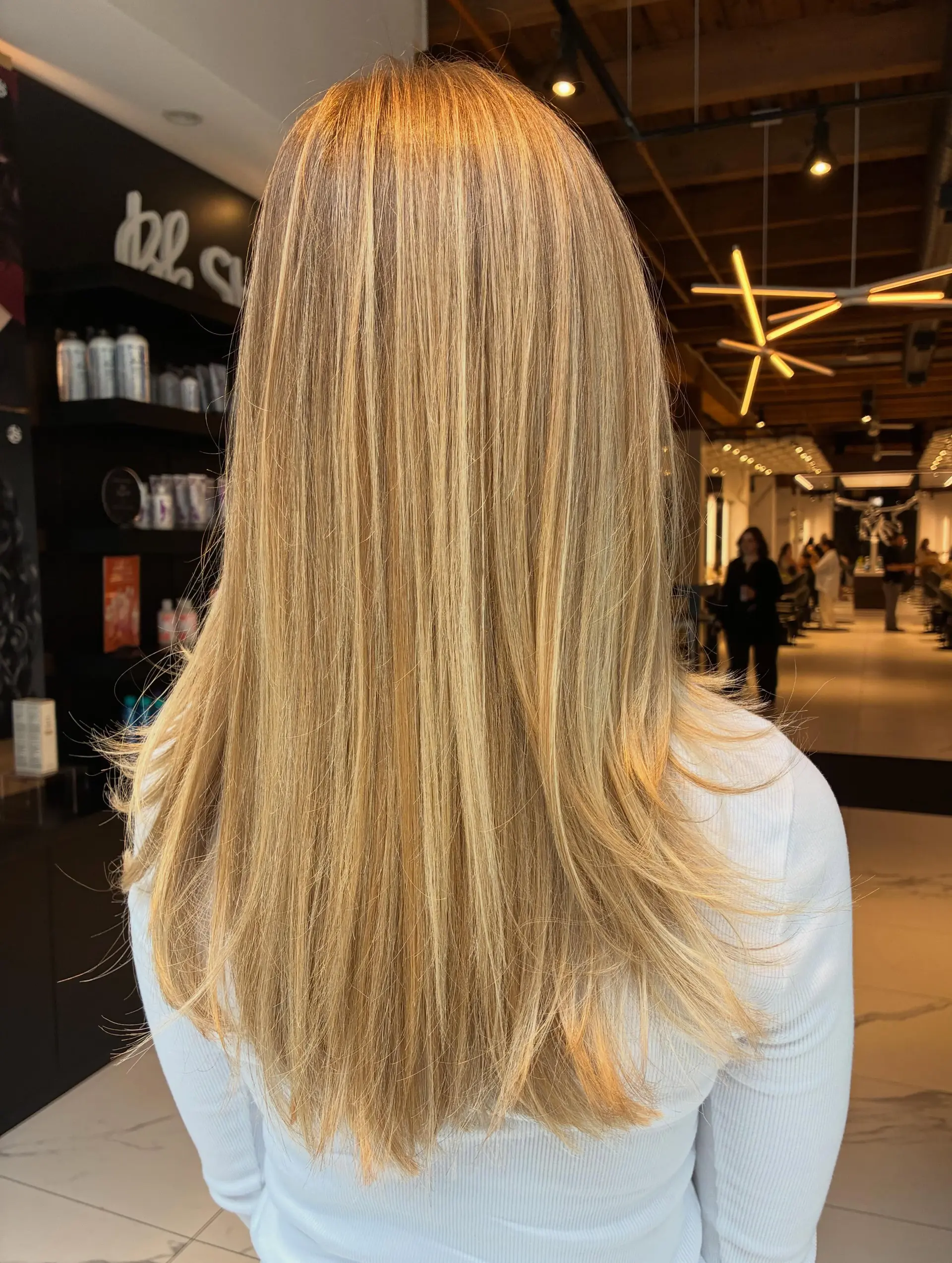 Long, smooth blonde hair featuring full dimensional highlights, a soft root melt, and gently layered ends. 1